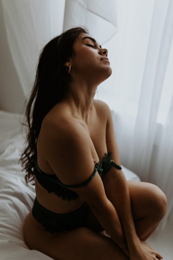Woman posing sensually in lingerie for a boudoir session. 