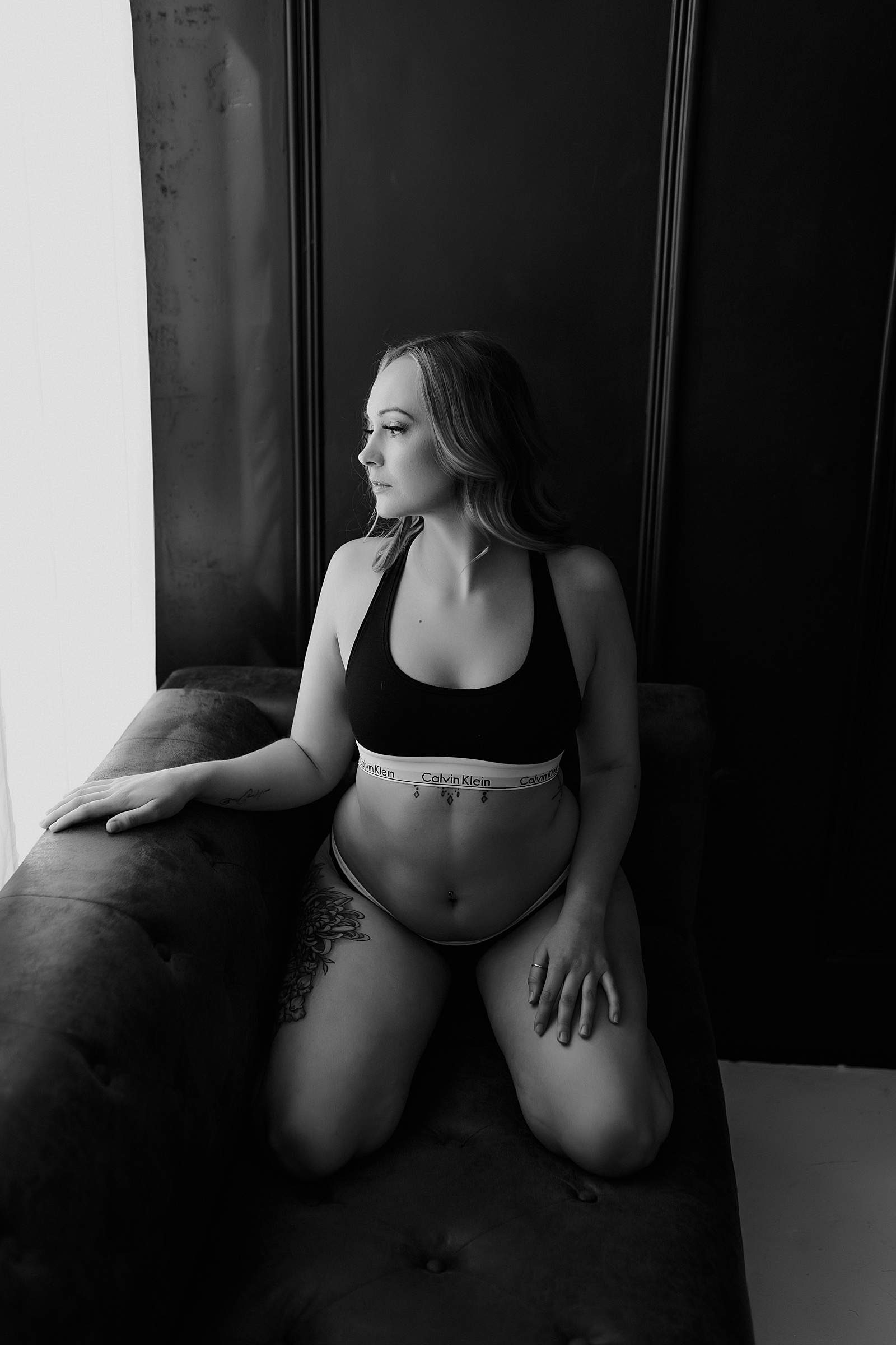 Woman in two piece Calvin Klein set on a couch of a boudoir studio 