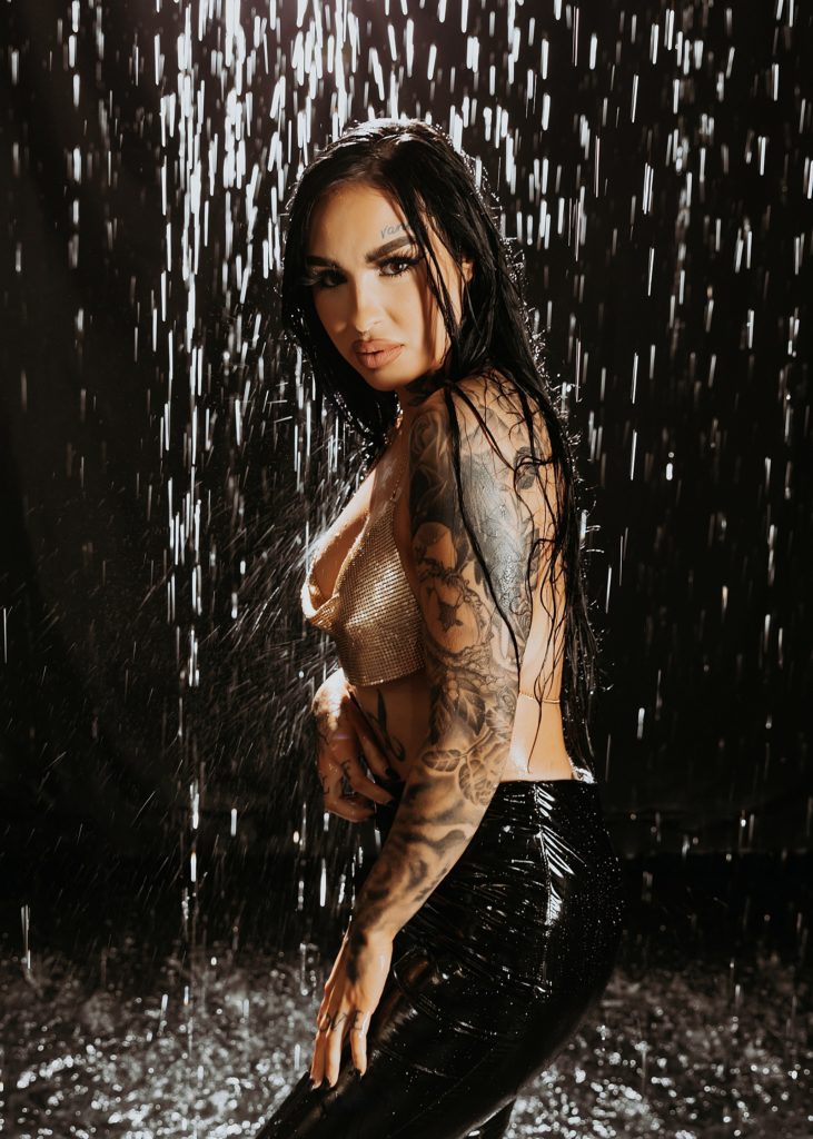 Woman with tattoos and gold top under water in a photography studio in Minnesota. 