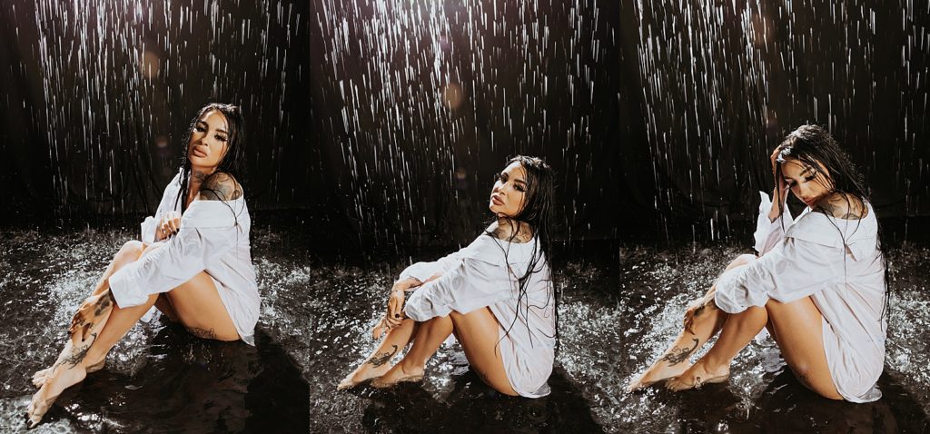 woman in white shirt sitting on the floor under a rain machine at a photo shoot