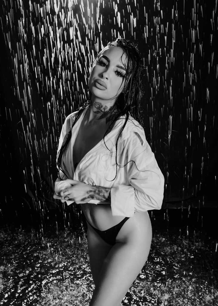 Woman in white shirt and black underwear surrounded by fake rain at a Minneapolis photo shoot.