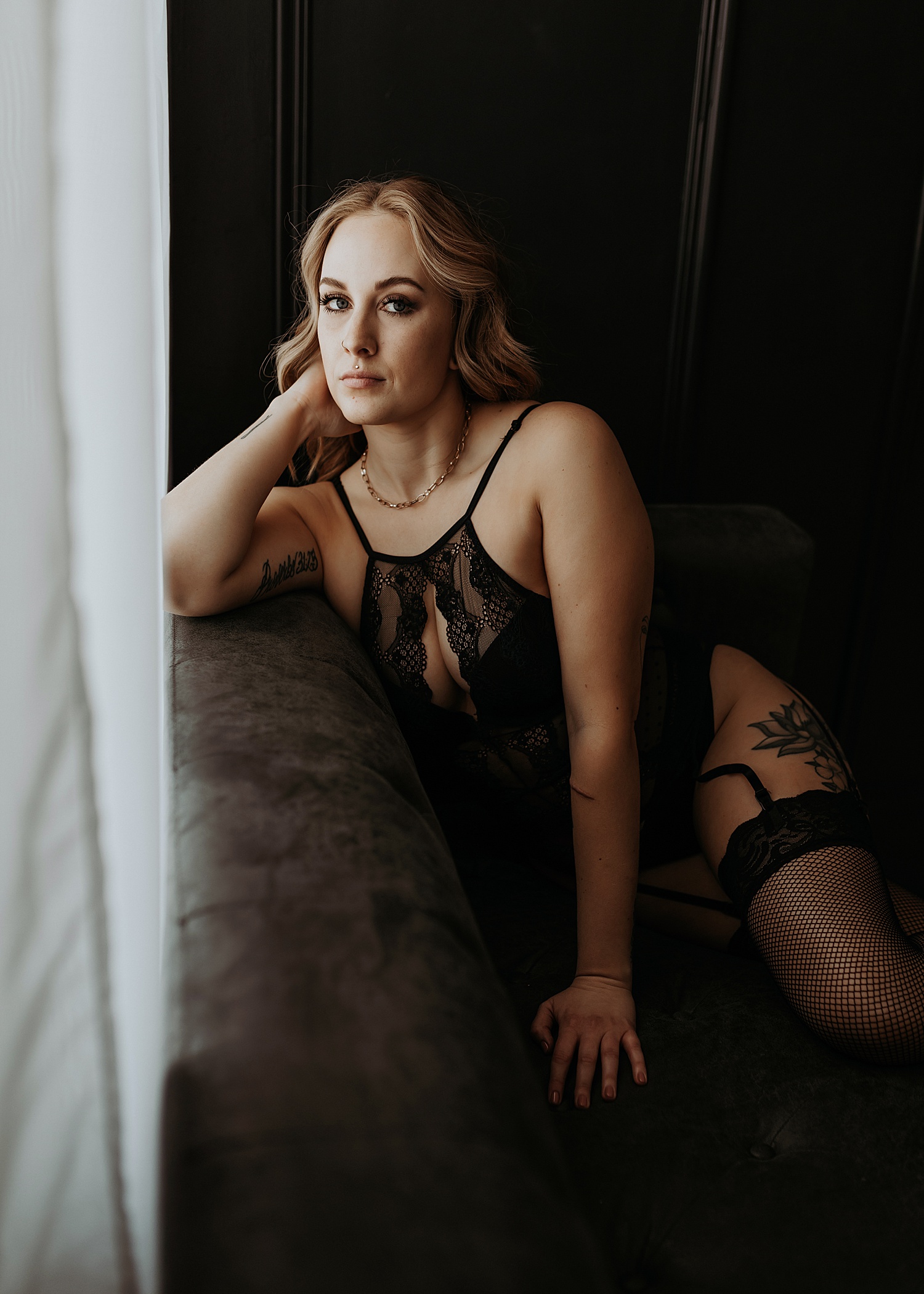 Woman in black lace lingerie sitting on the couch for boudoir session 