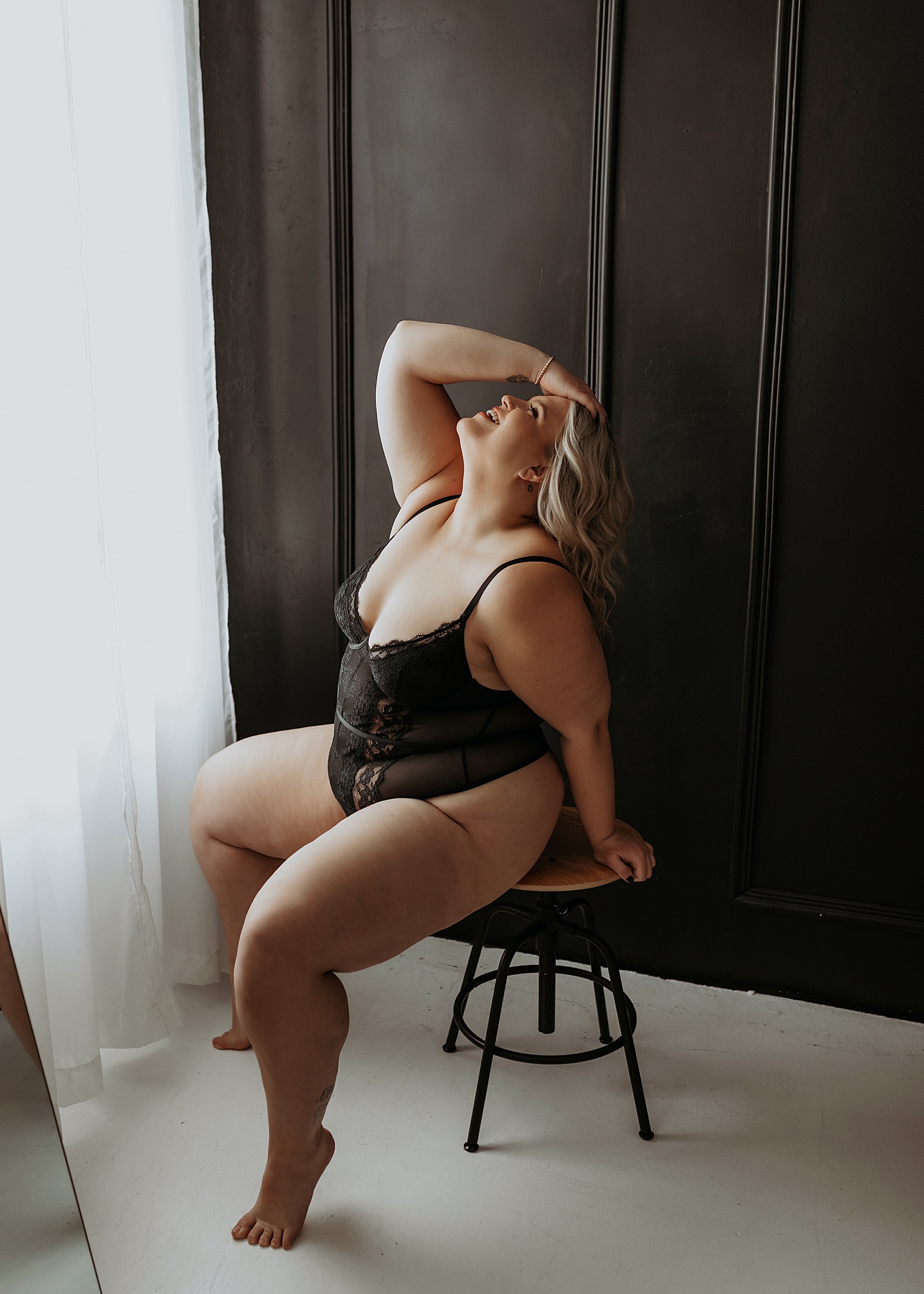 Woman in sheer bodysuit lingerie on a stool by boudoir photographer Mary Castillo 