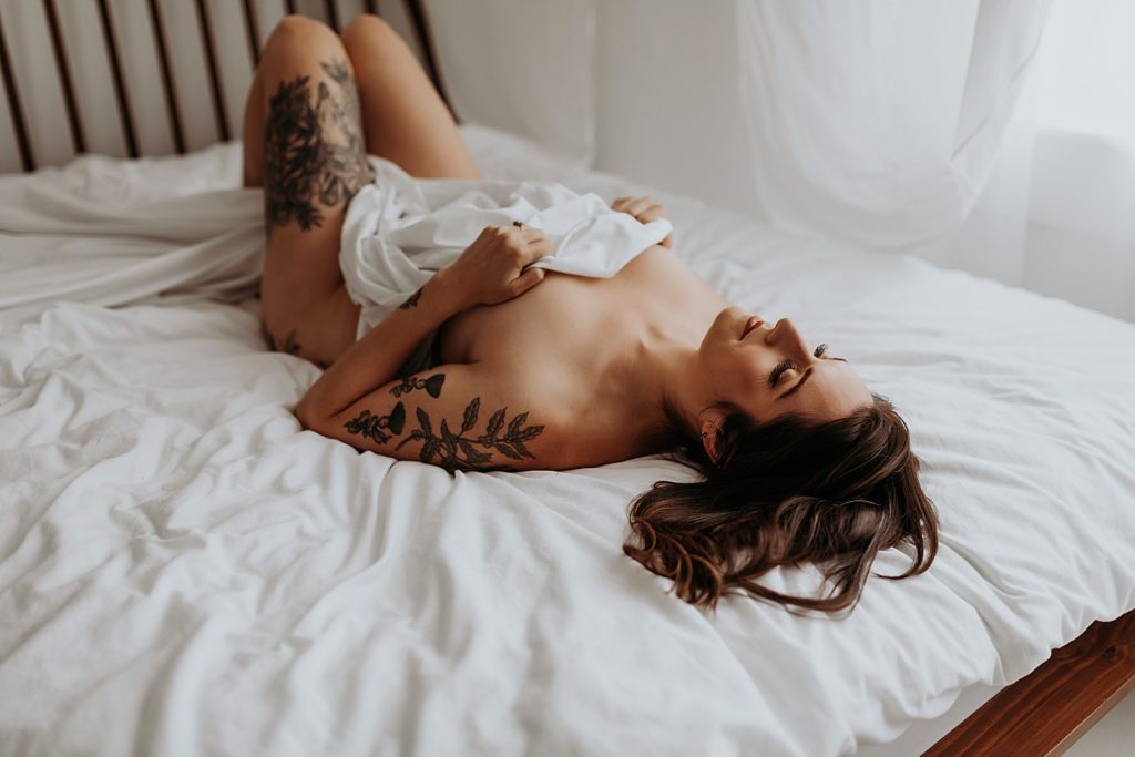 brunette woman in the nude lying across a bed at Minneapolis studio