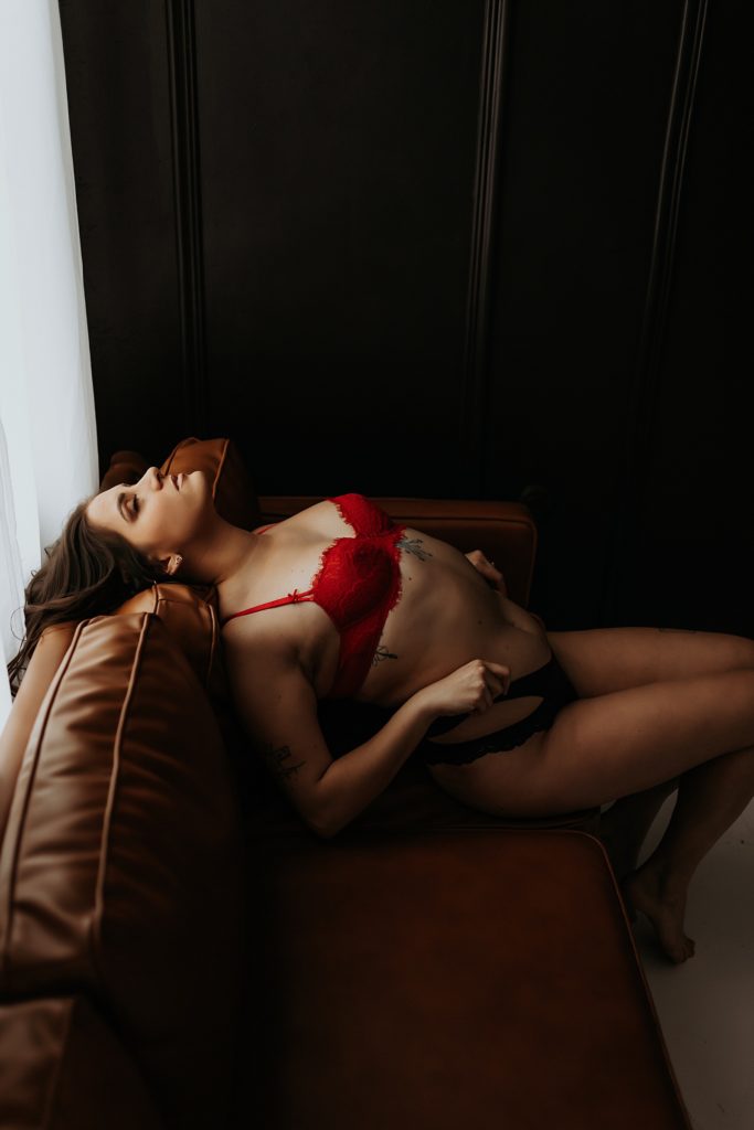 Brunette in red bra on a couch for intimate portrait photo shoot