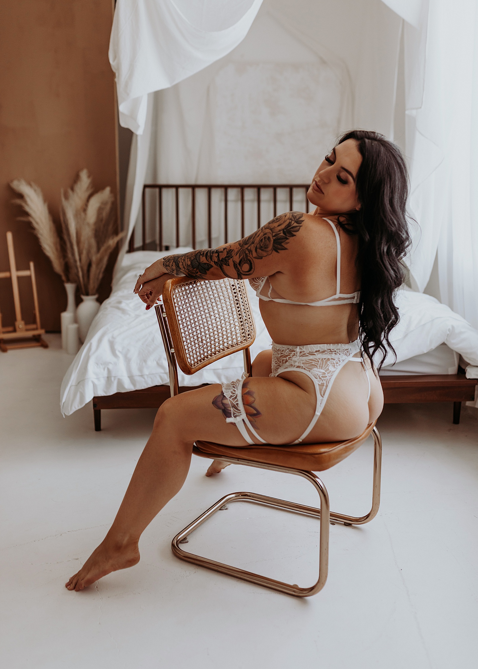 Woman sitting on a chair in white lace lingerie by a Minneapolis boudoir photographer