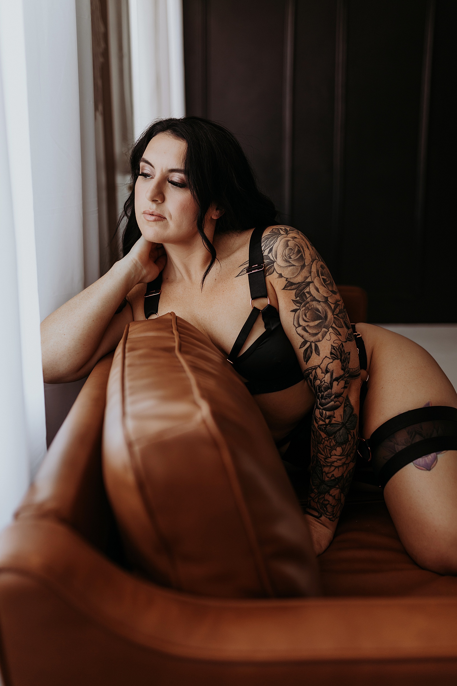 Woman with tattoos on a couch in studio by a Minneapolis boudoir photographer