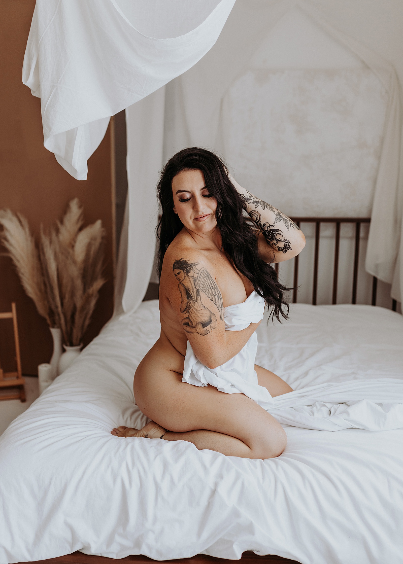 Nude woman kneeling on a bed in modern photo studio in Minnesota 