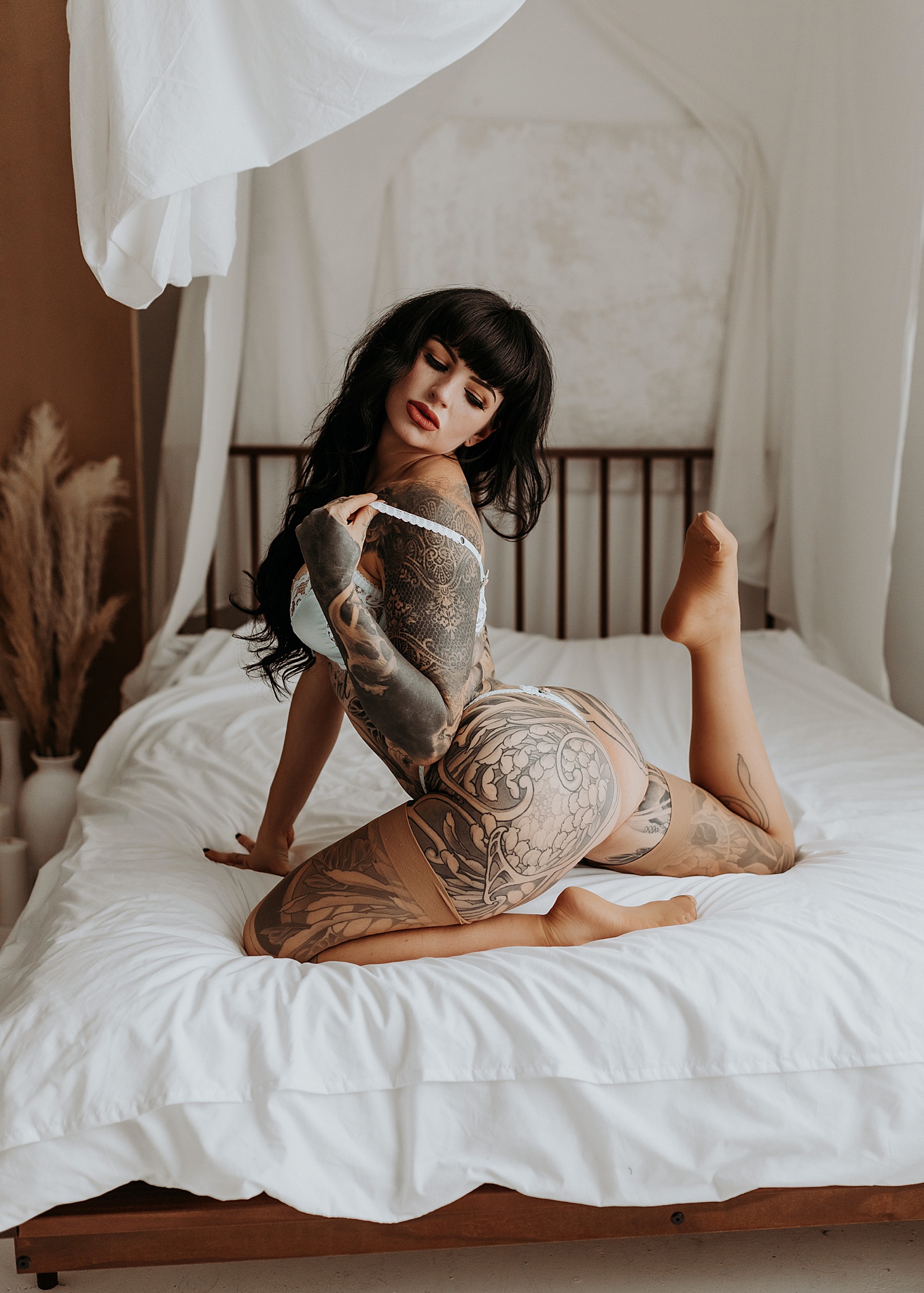 Woman with black hair kneeling on bed at studio by Minneapolis Boudoir Photographer