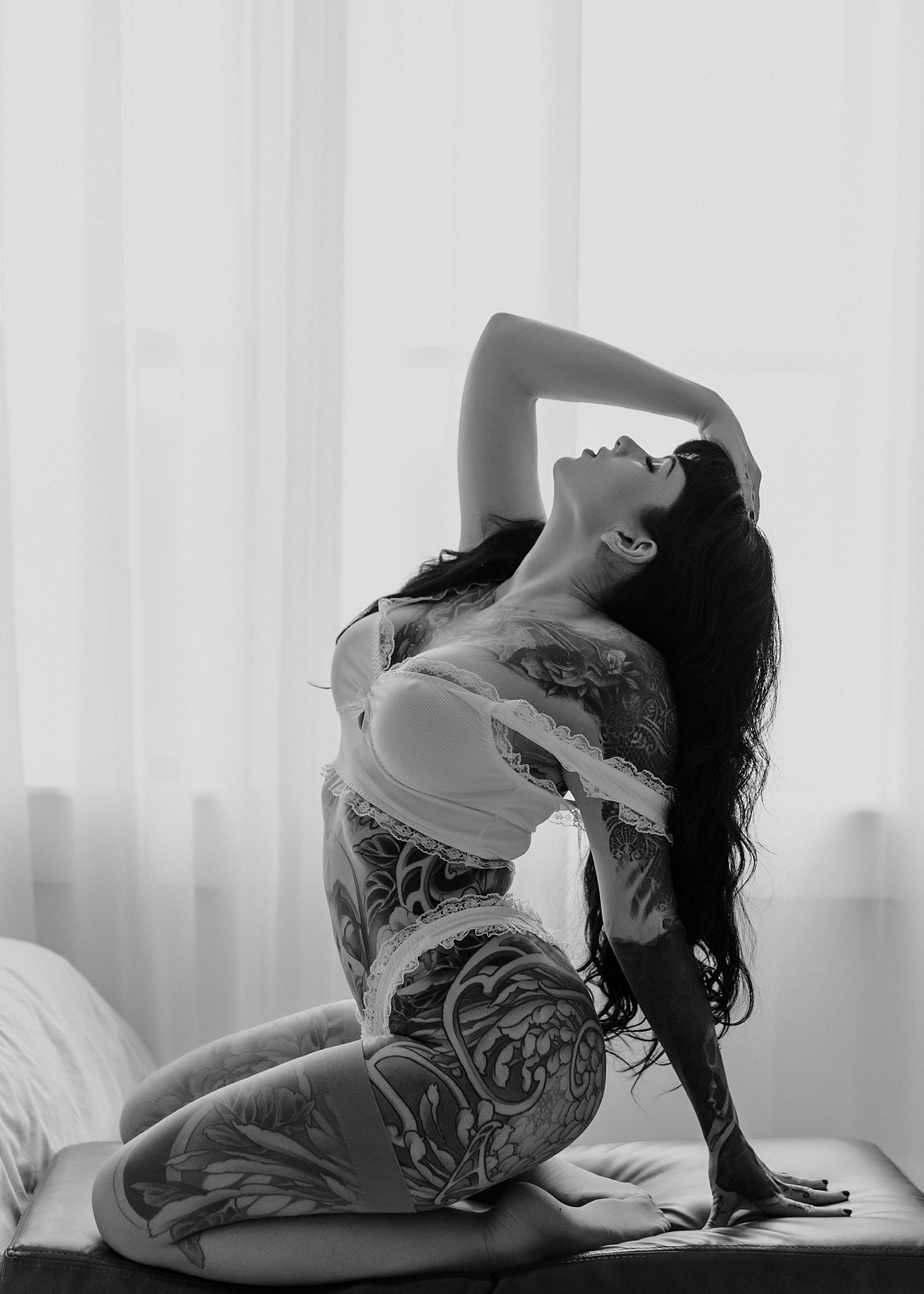 Woman with full body tattoos in white lingerie for elevated pin-up vibes session