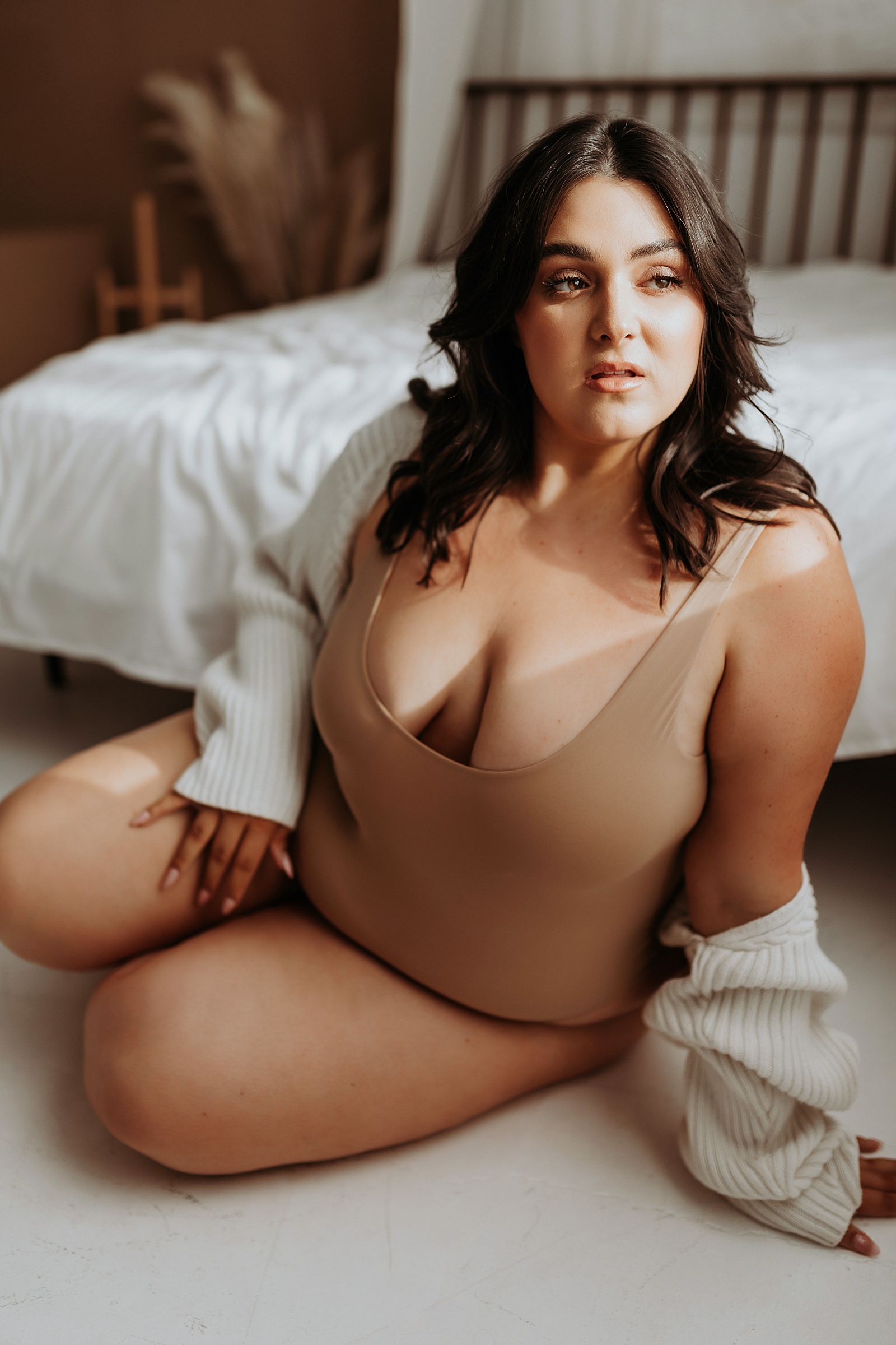 Model with brown eyes leaning against a bed for body activist shoot