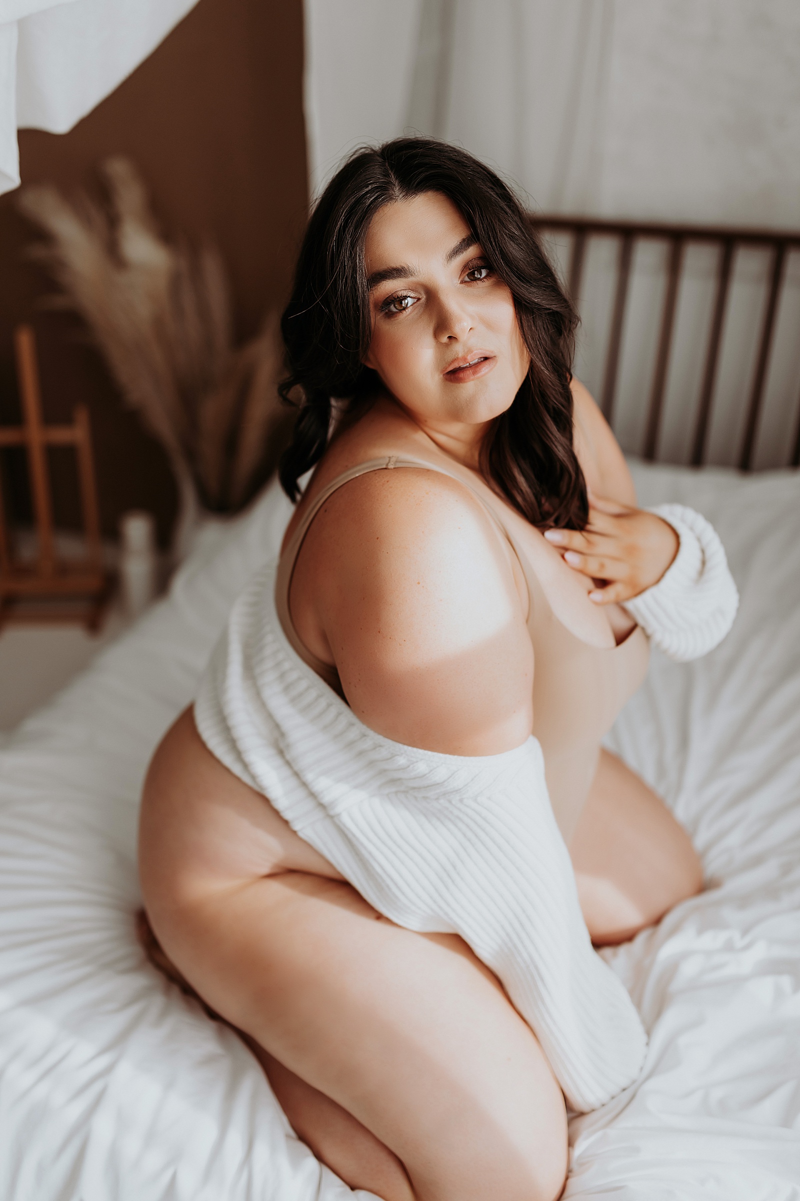 Brunette woman in nude lingerie and white sweater by Minneapolis boudoir photographer