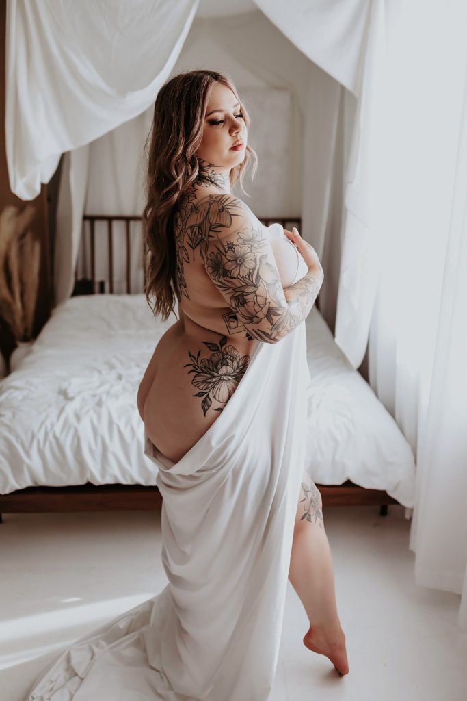 nude client with tattoos covering herself with white sheet by Mary Castillo Photography