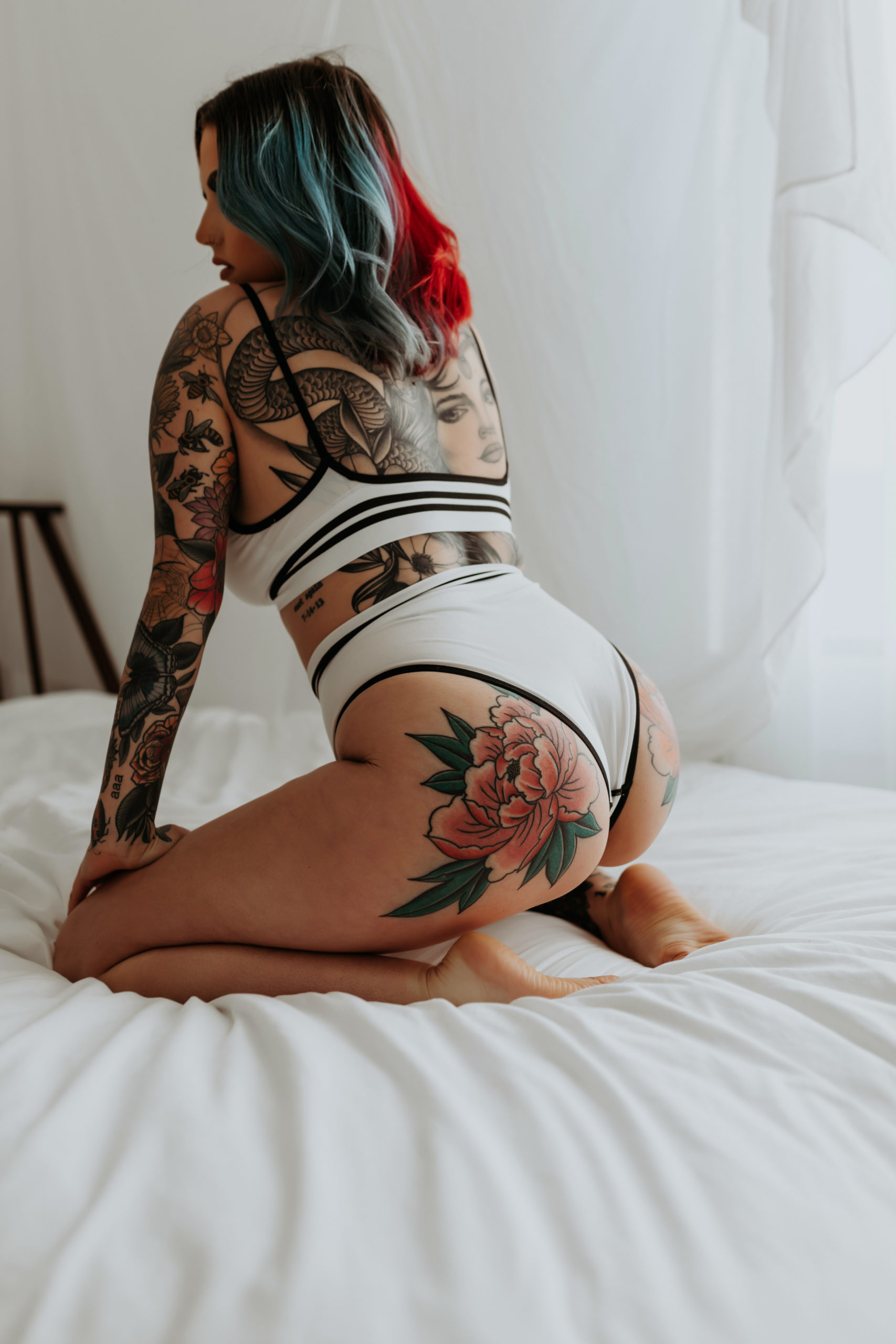 Model and Makeup Artist kneels on hands and knees on bed for 