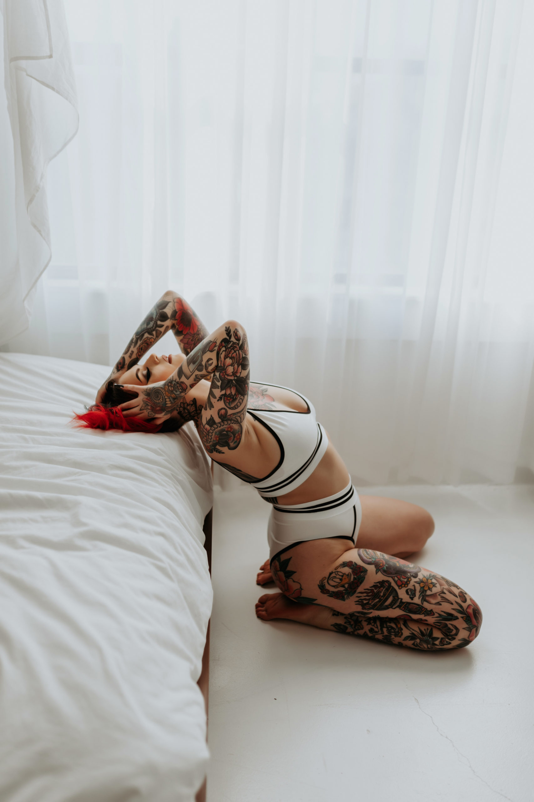 Woman grabs hair and face while leaning against bed for Minneapolis Boudoir Photographer