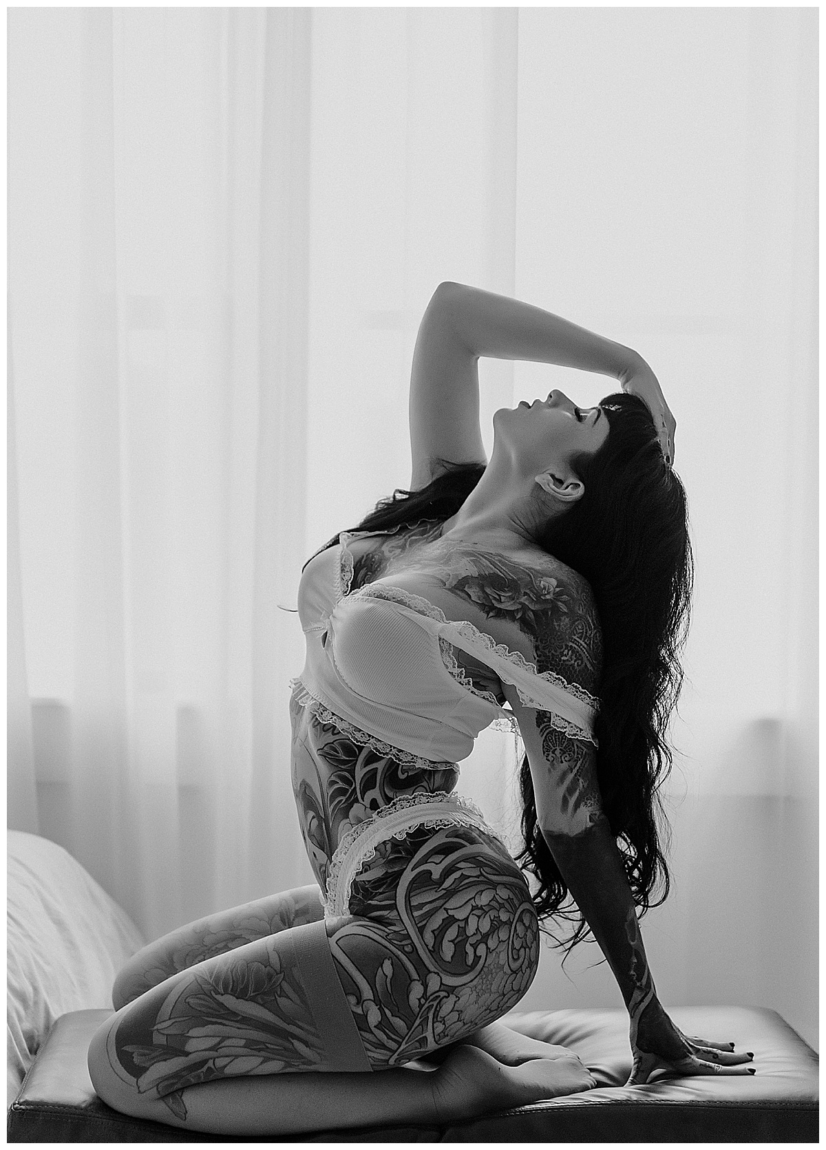 Tattooed woman leans back on couch for Minneapolis Boudoir Photographer