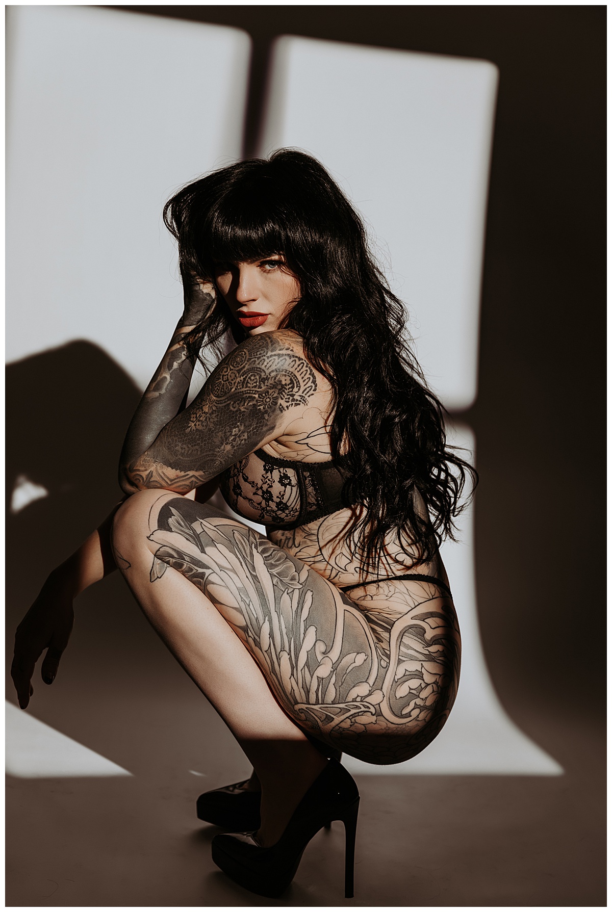 Tattooed woman sits in front of light for Mary Castillo Photography