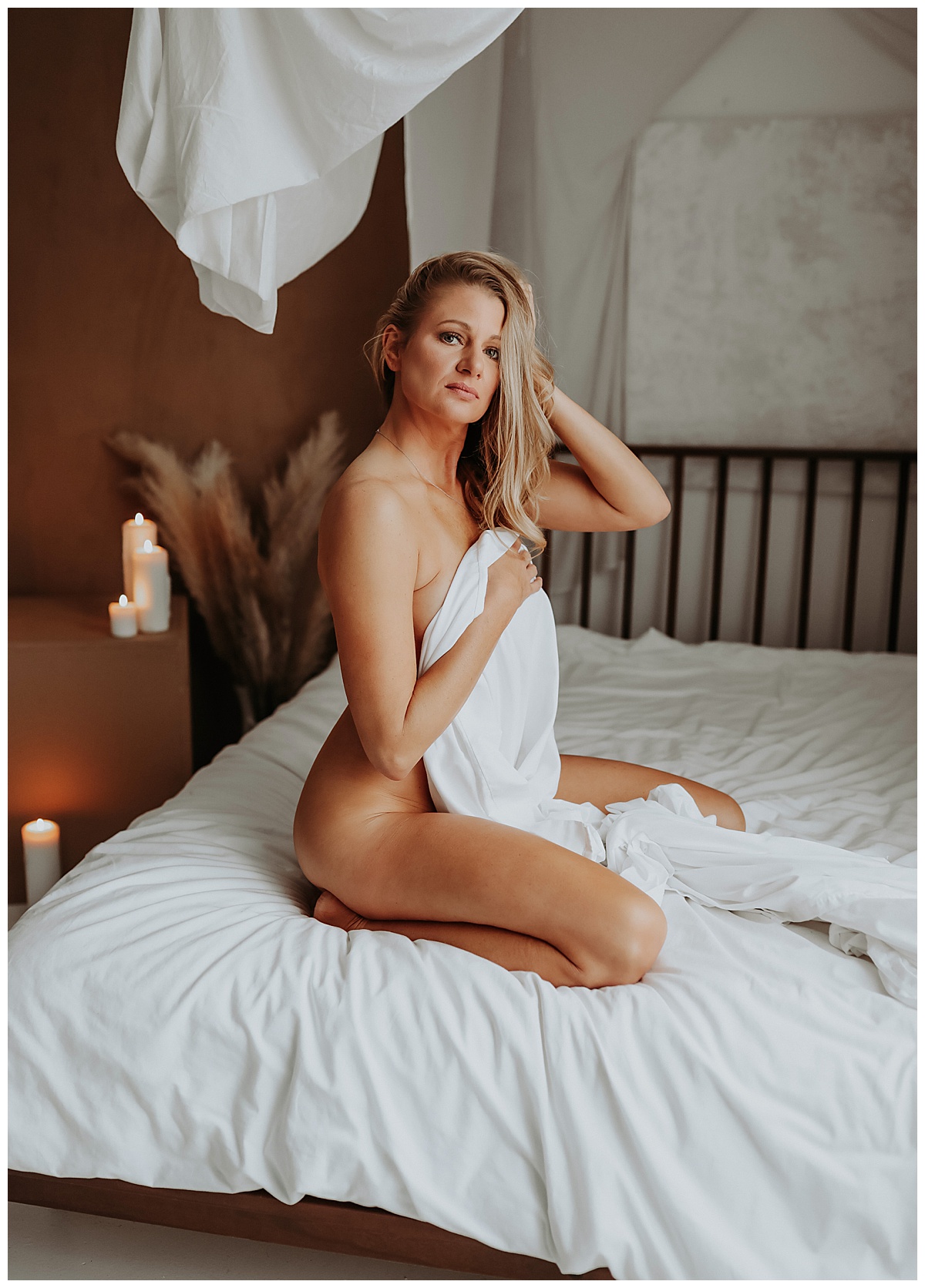 Blonde sits on bed with white sheet for Minneapolis Boudoir Photographer