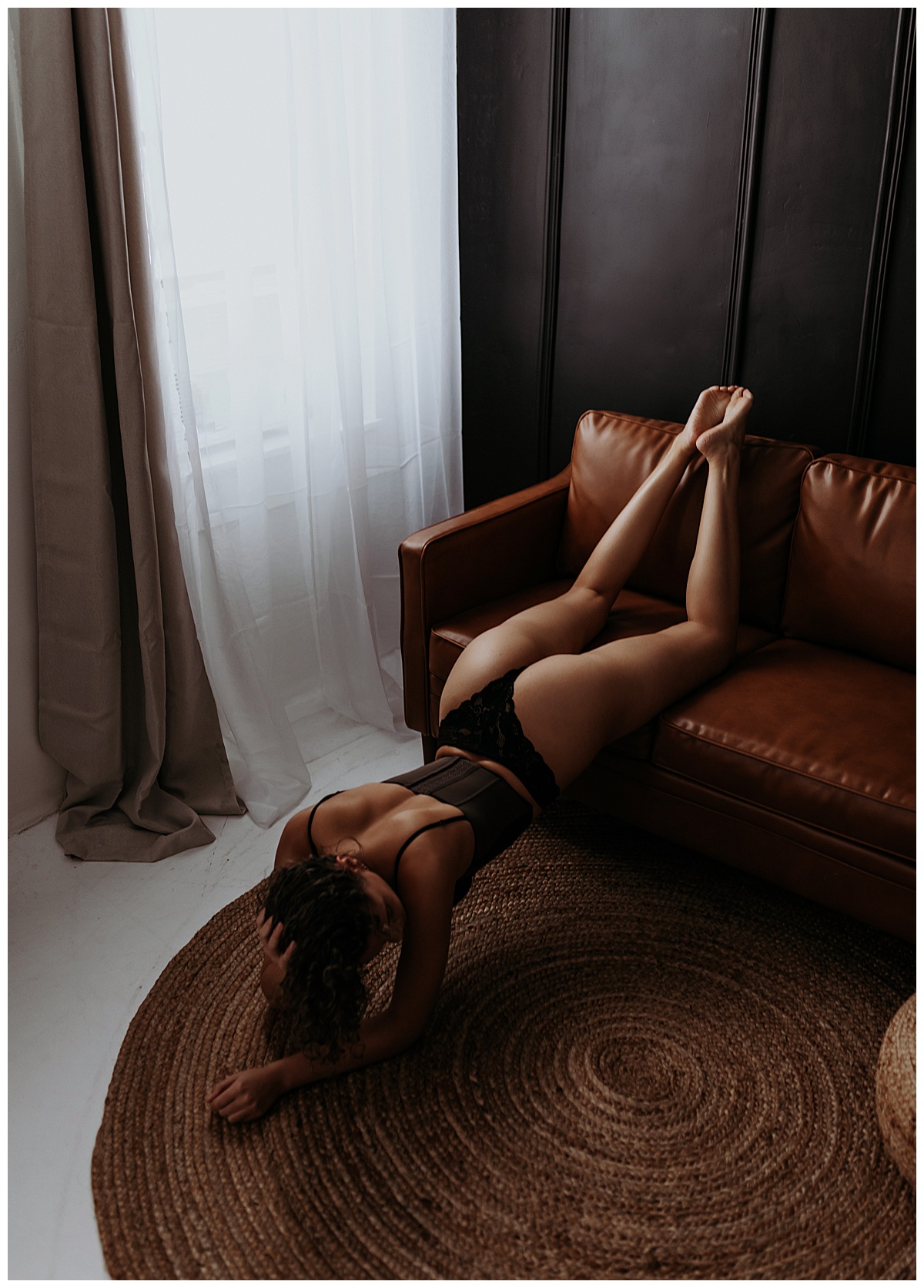Adult in black lingerie leaning over couch for Mary Castillo Photography