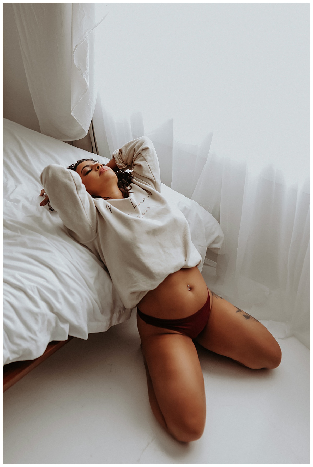 Lady in sweater leans over edge of bed for Mary Castillo Photography