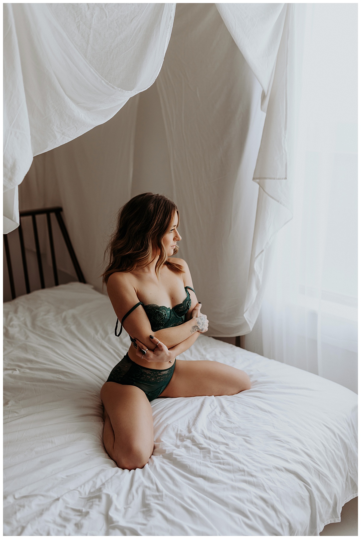 Adult hugs and holds body in lingerie sitting on bed for Minneapolis Boudoir Photographer