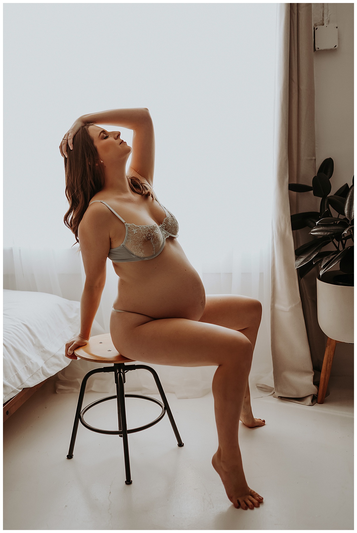 Pregnant lady sits on barstool in lingerie for Maternity Boudoir session