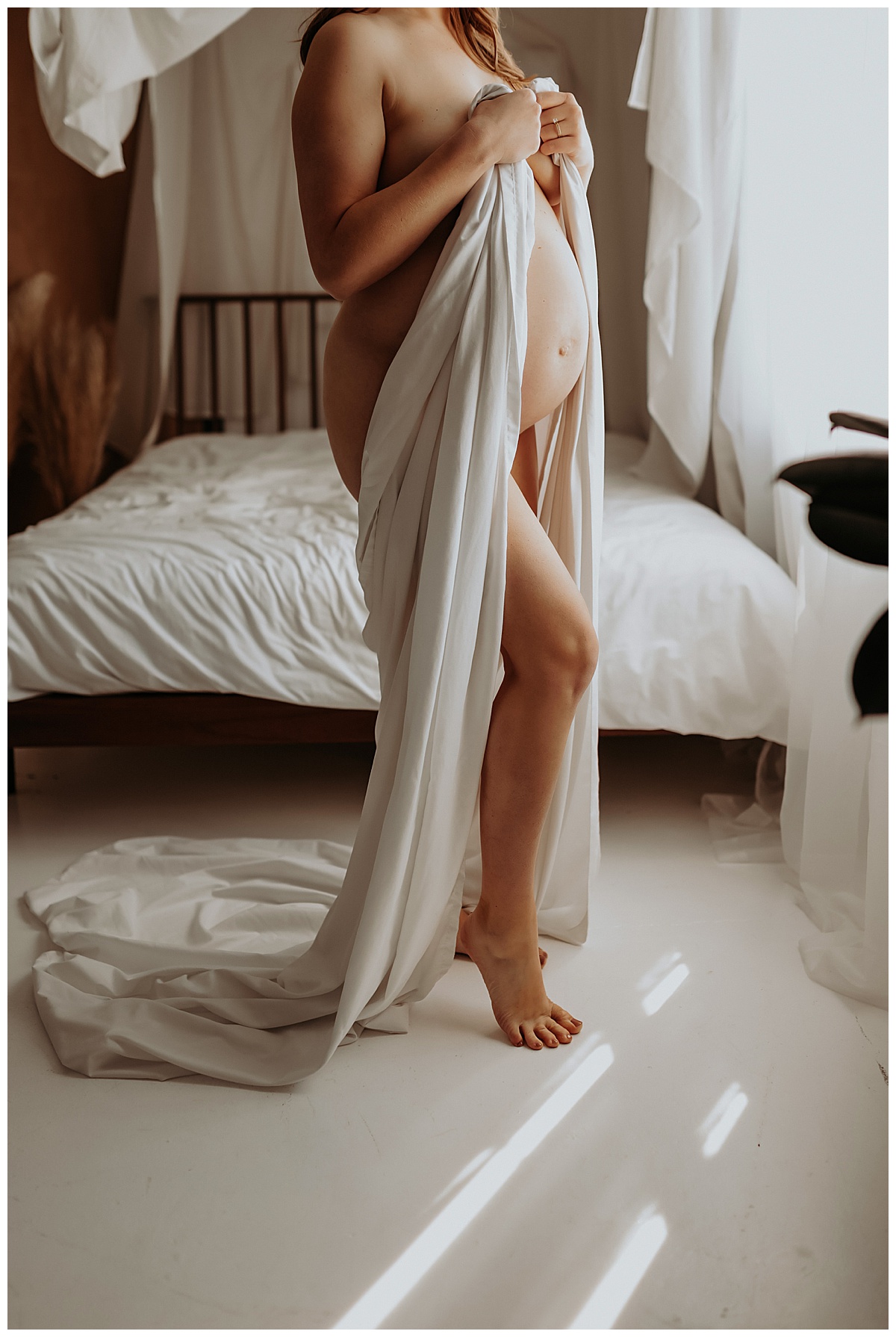 Adult covers body with white sheet for Mary Castillo Photography