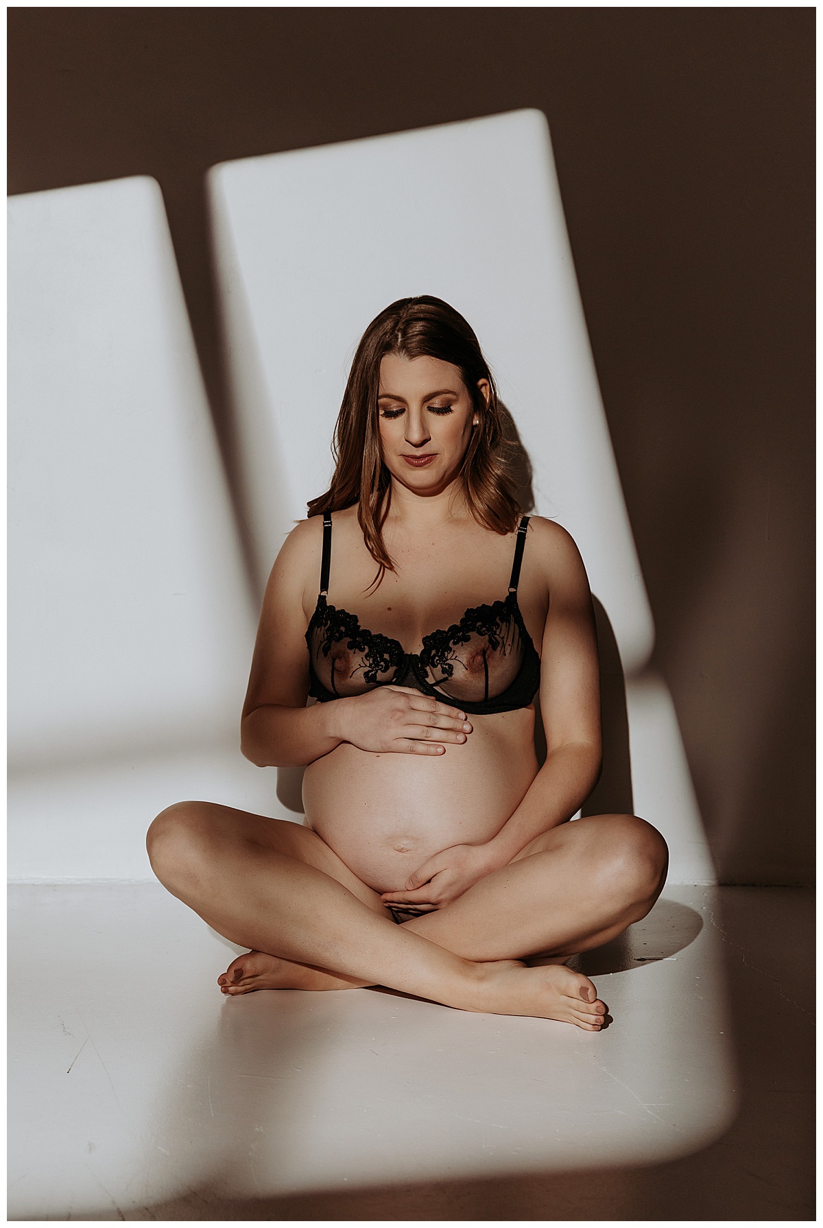Pregnant lady looks down at pregnant belly for Maternity Boudoir session