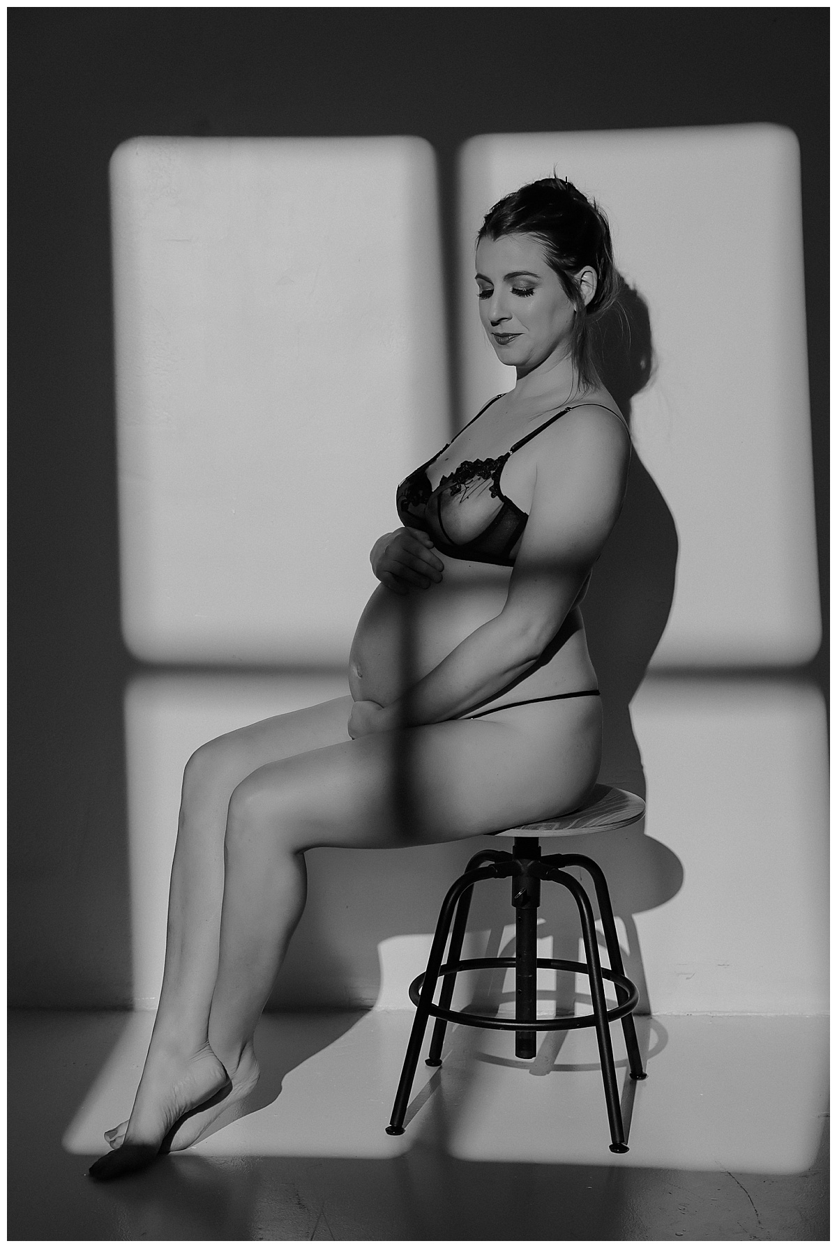 Mother sits on stool and grabs belly for Minneapolis Boudoir Photographer