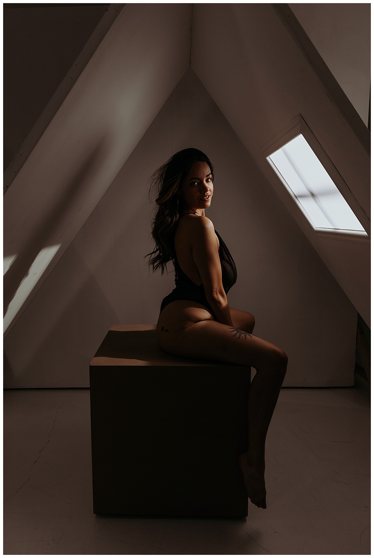Female sits in light in black lingerie for  Minneapolis Boudoir Photographer