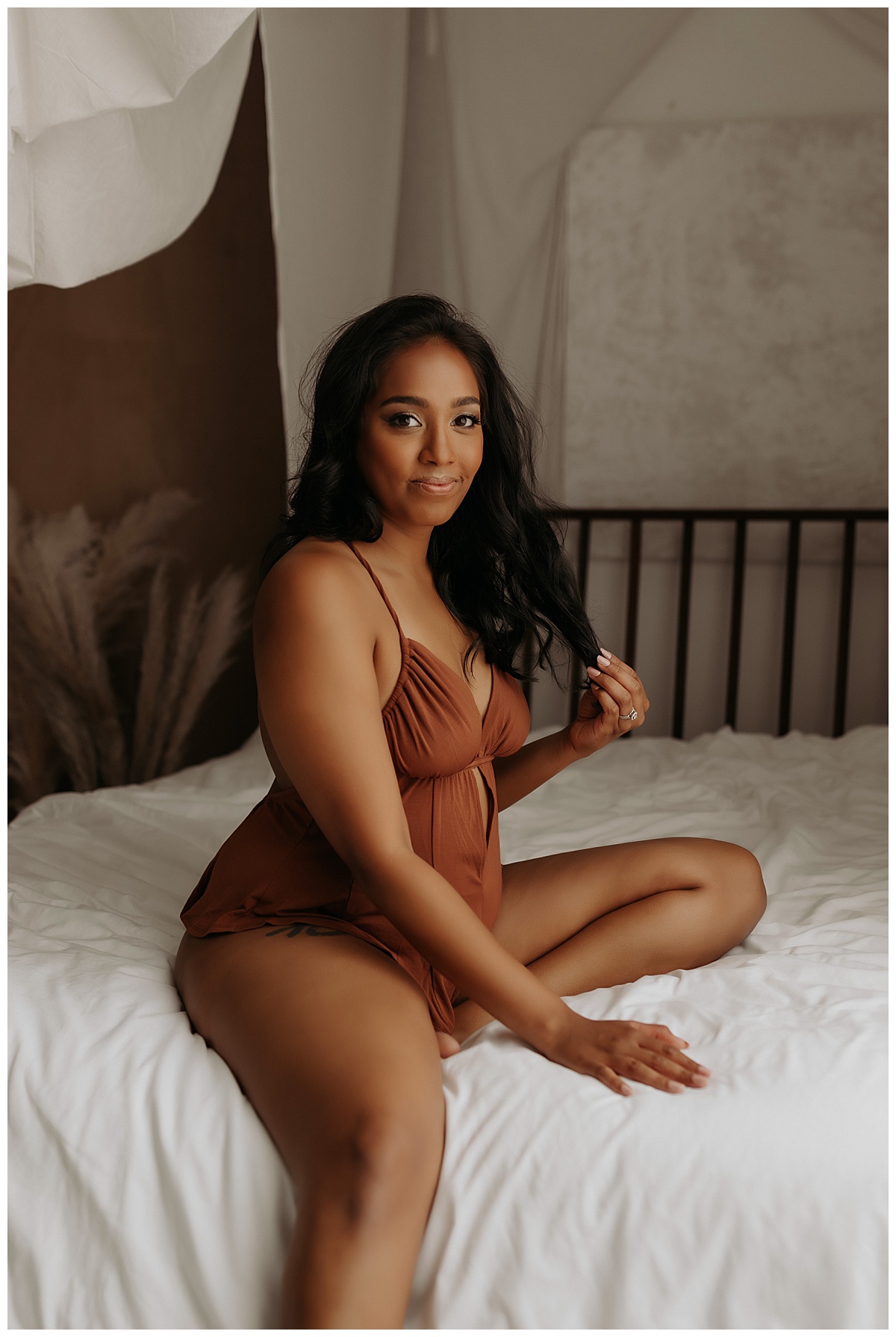 Mother runs fingers through while sitting on the bed for Minneapolis Boudoir Photographer
