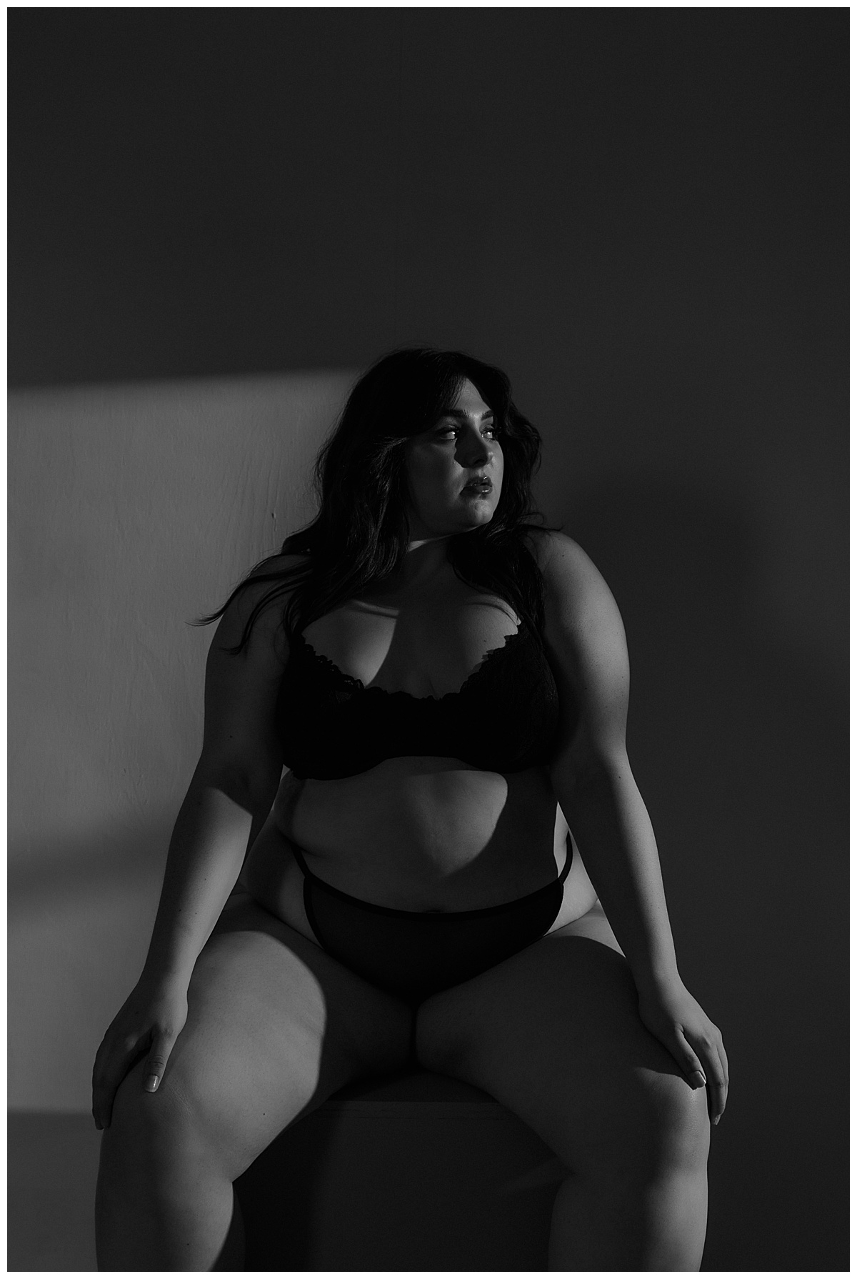 Female rests hands on knees wearing black lingerie for Minneapolis Boudoir Photographer