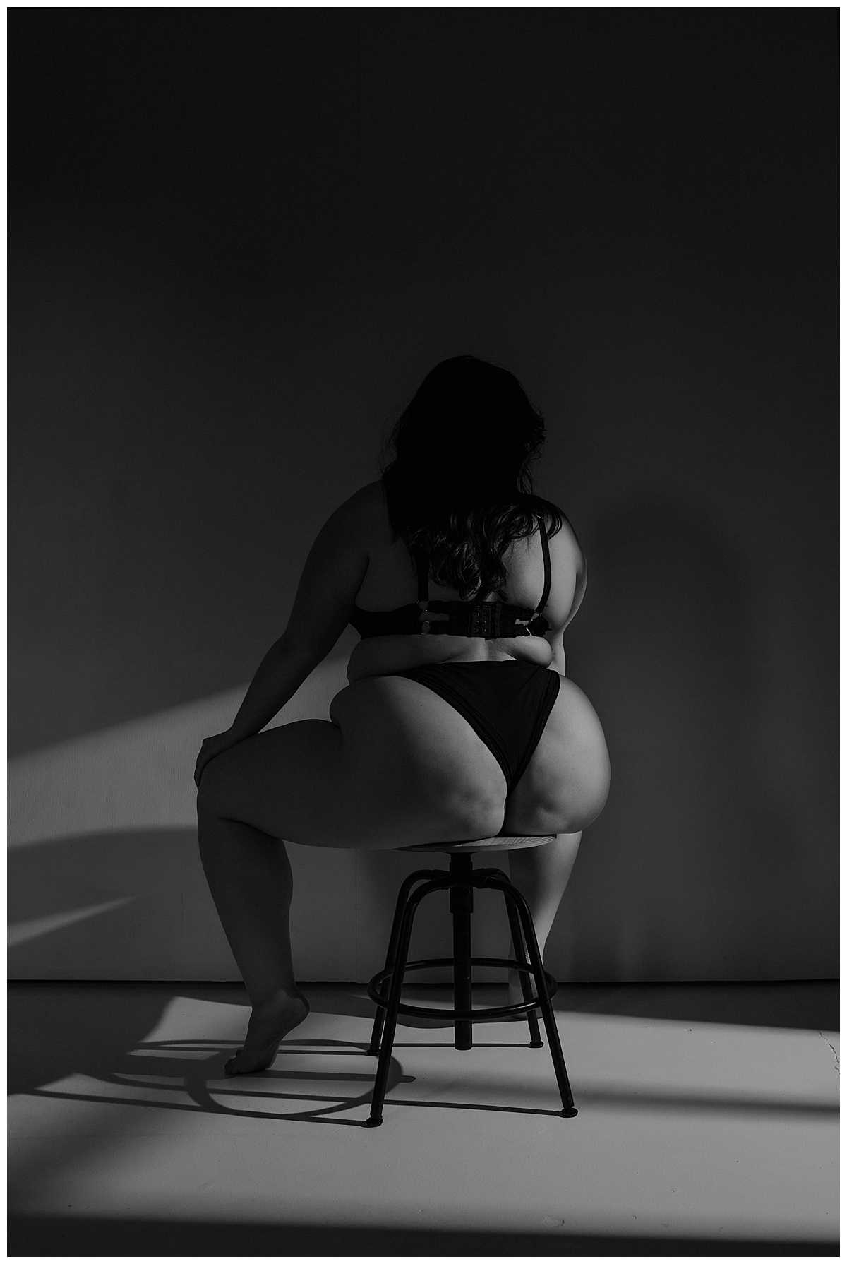 Woman sits on the stool wearing glingerie in the Studio Lighting