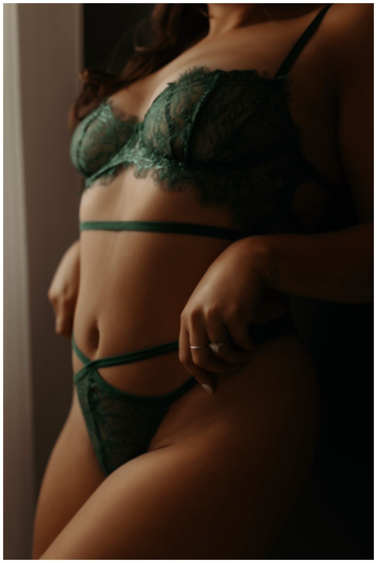 Adult tugs at her green lingerie for Minneapolis Boudoir Photographer