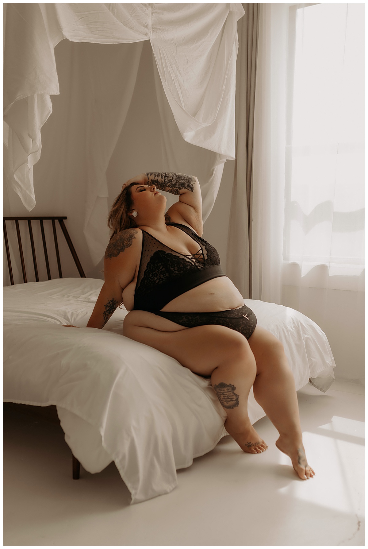 Girl leans back onto the bed wearing black lingerie from Torrid Lingerie