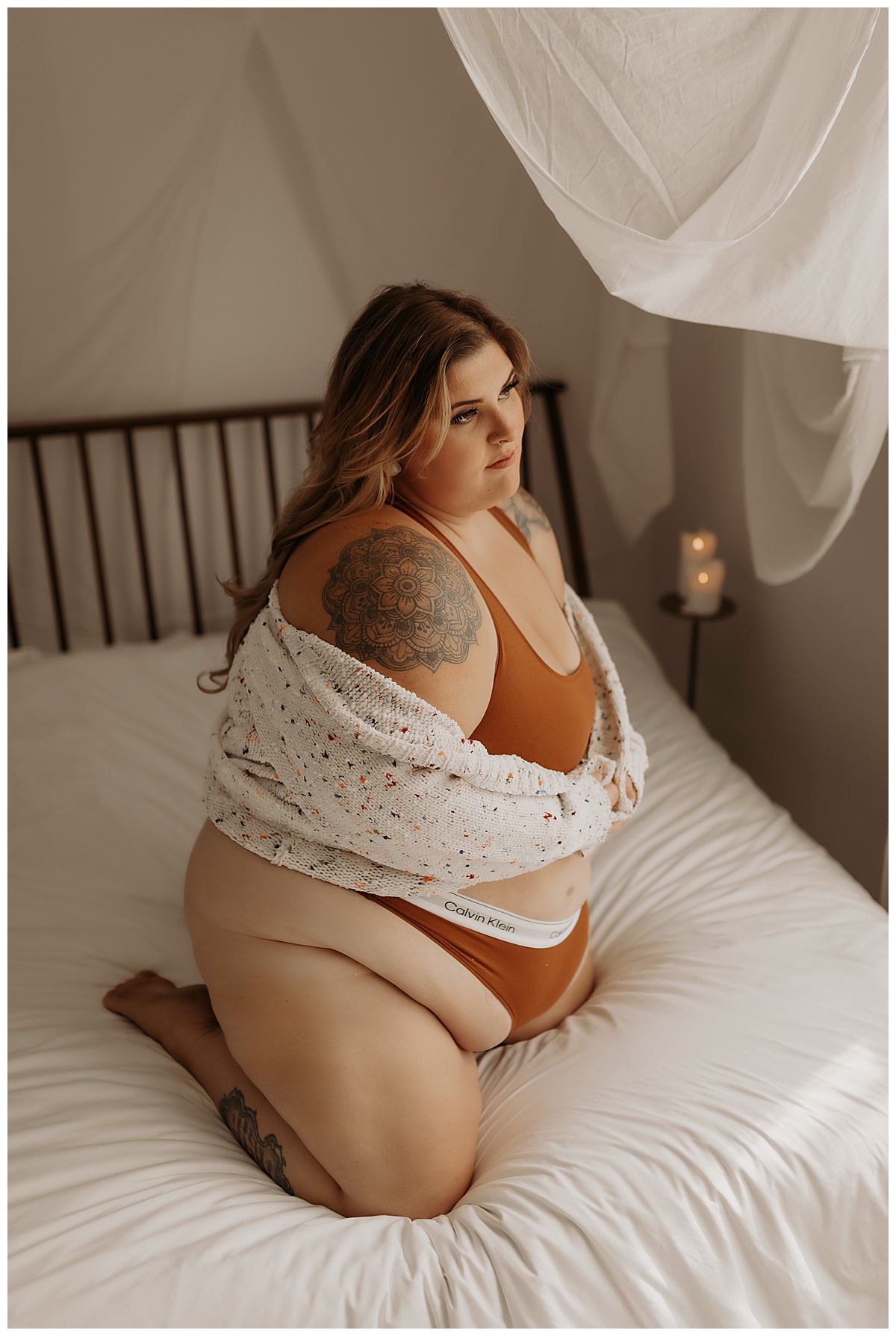 Female sits on the bed wearing lingerie for Minneapolis Boudoir Photographer