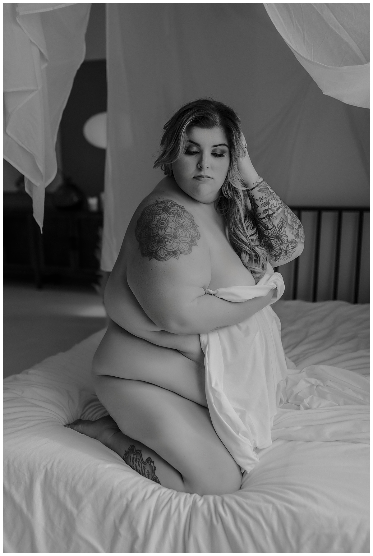 Person kneels on a bed covering her body with a sheet for Mary Castillo Photography