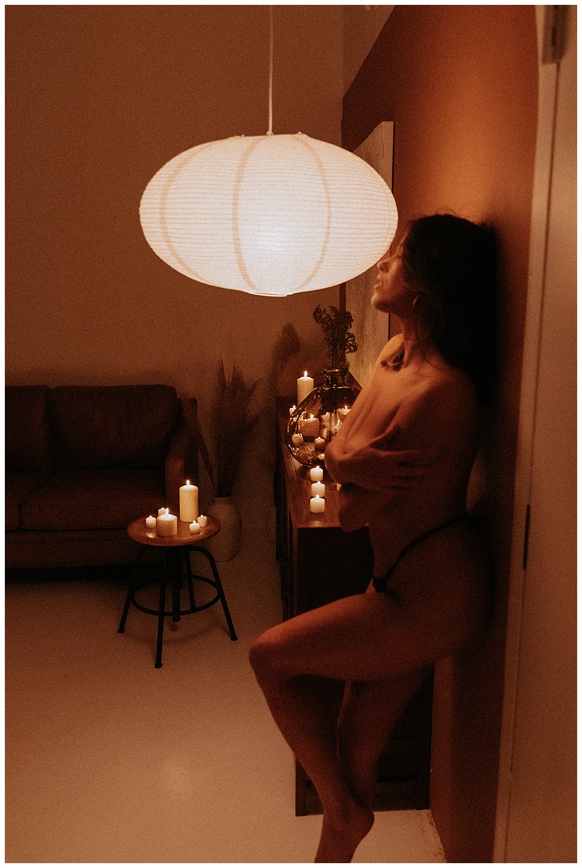 Person covers her body with her arms during her Candlelit Boudoir session