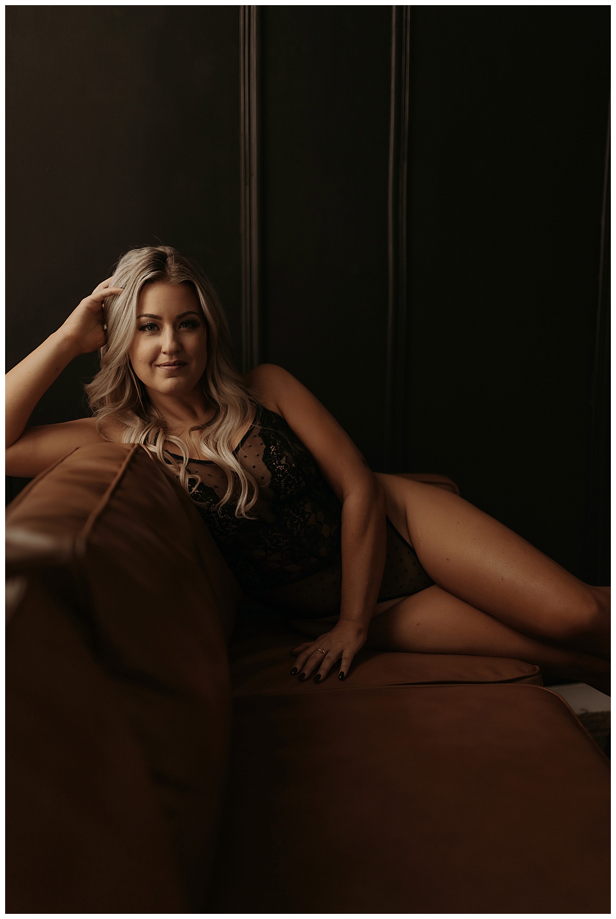 Adult sits on the sofa wearing black lingerie for Minneapolis Boudoir Photographer