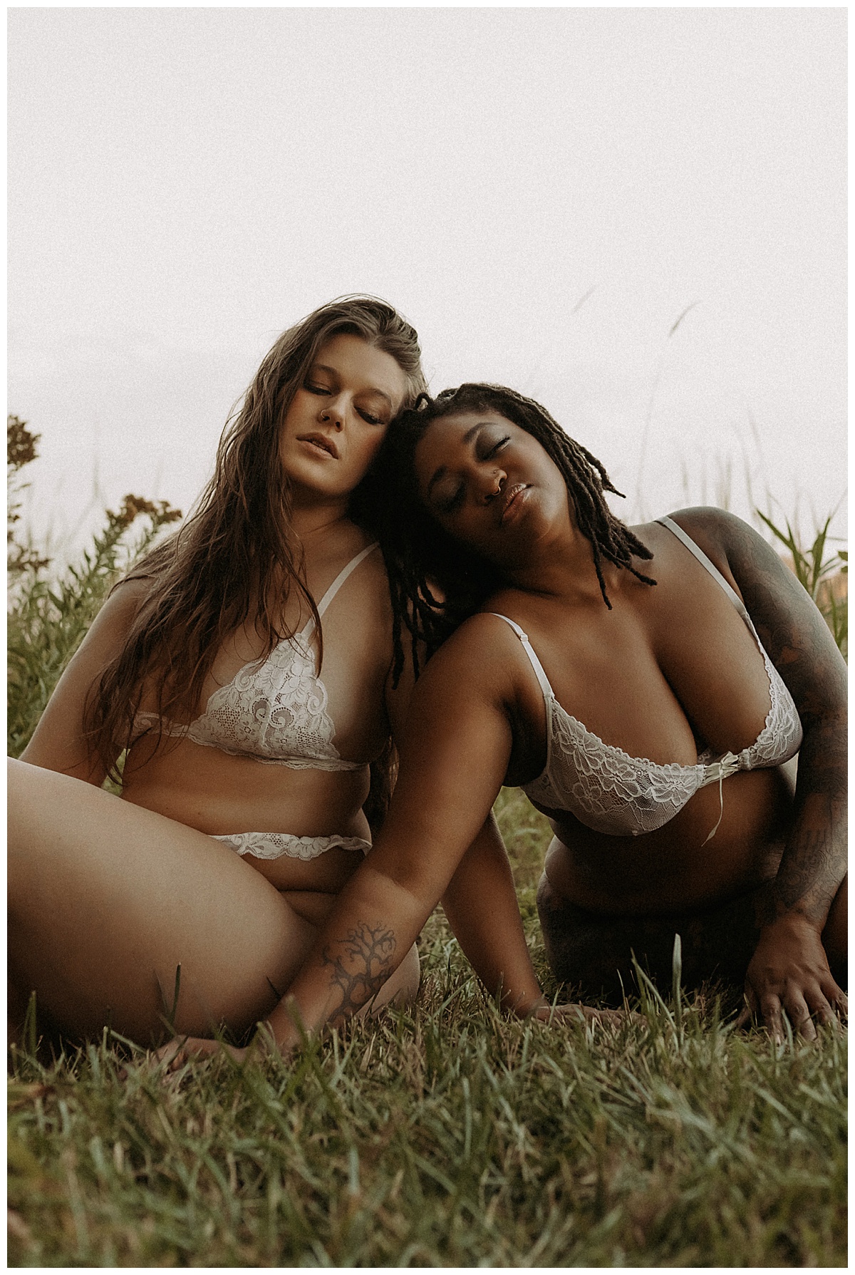 Two people sit on the ground wearing white lingerie for Minneapolis Boudoir Photographer