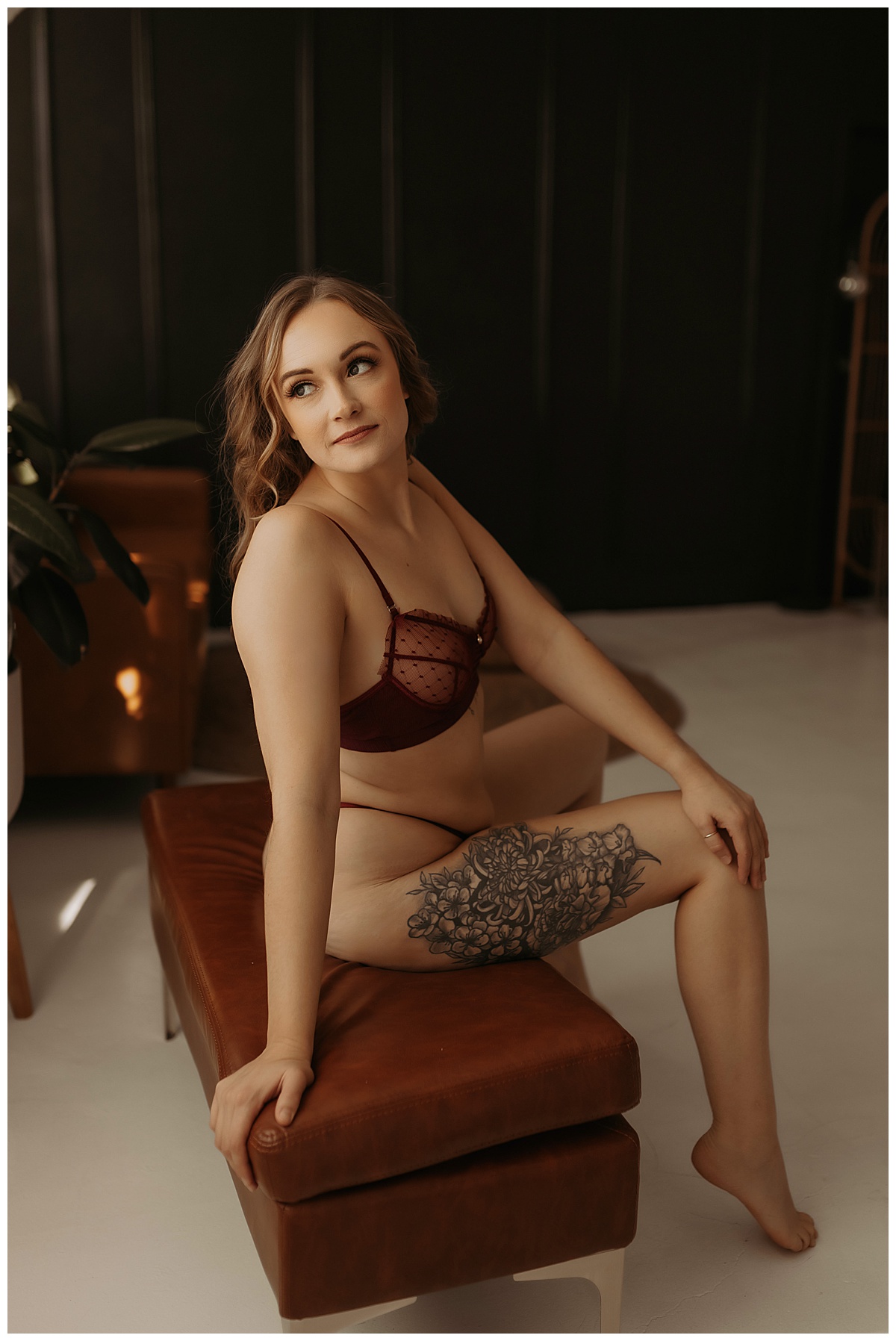 Woman sits on a couch bench wearing red lingerie for Minneapolis Boudoir Photographer