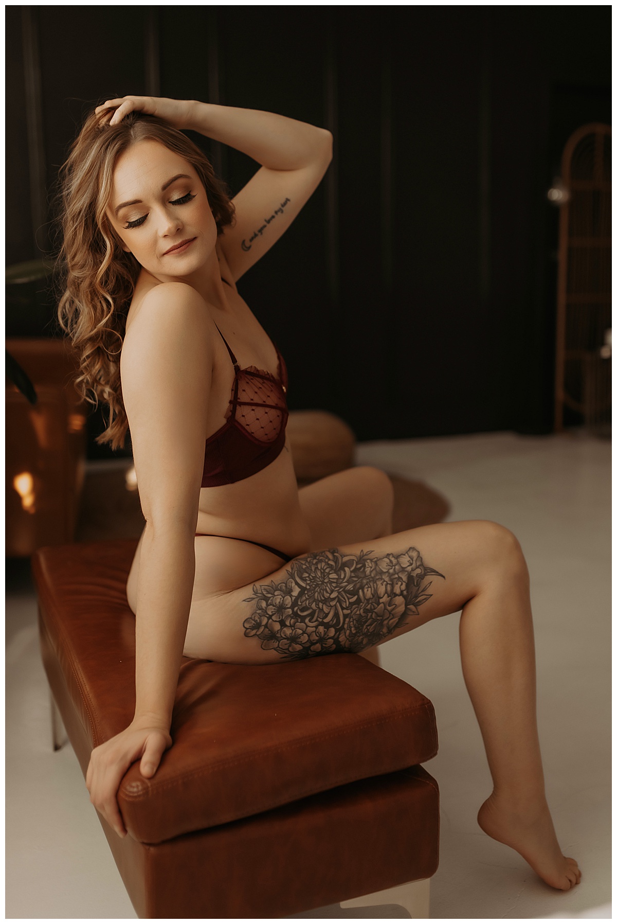 Adult sits on a couch bench wearing lingerie for Minneapolis Boudoir Photographer