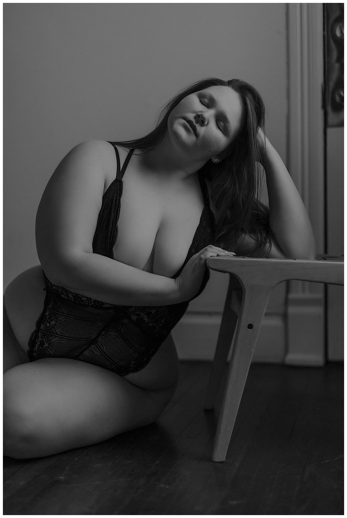 Adult leans onto a stool wearing black lingerie for Minneapolis Boudoir Photographer