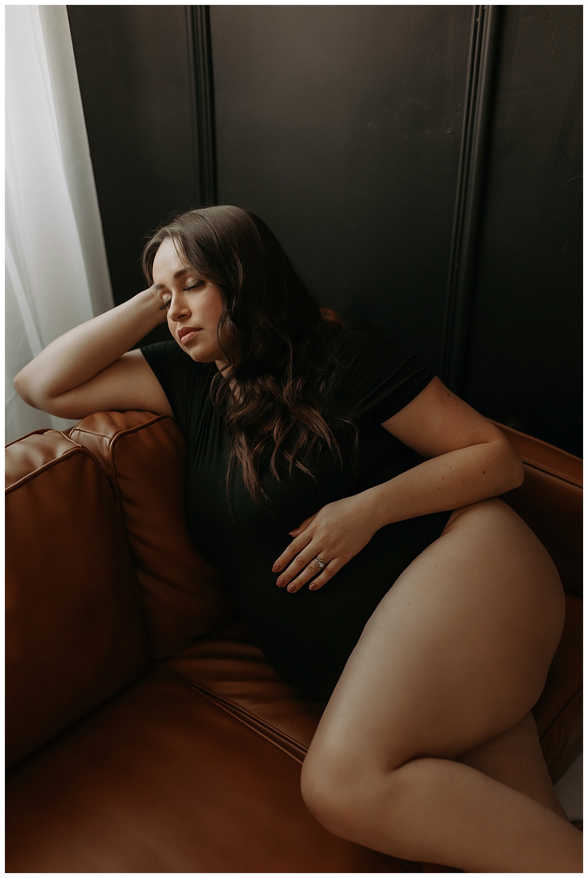 Adult lays on the couch holding her baby bump for Mary Castillo Photography