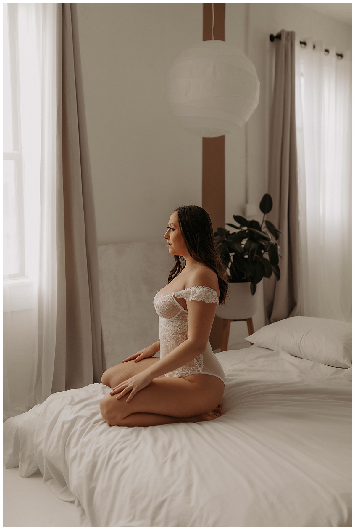 Woman sits on the bed wearing white lingerie showing the benefits of doing More Than One Boudoir Session