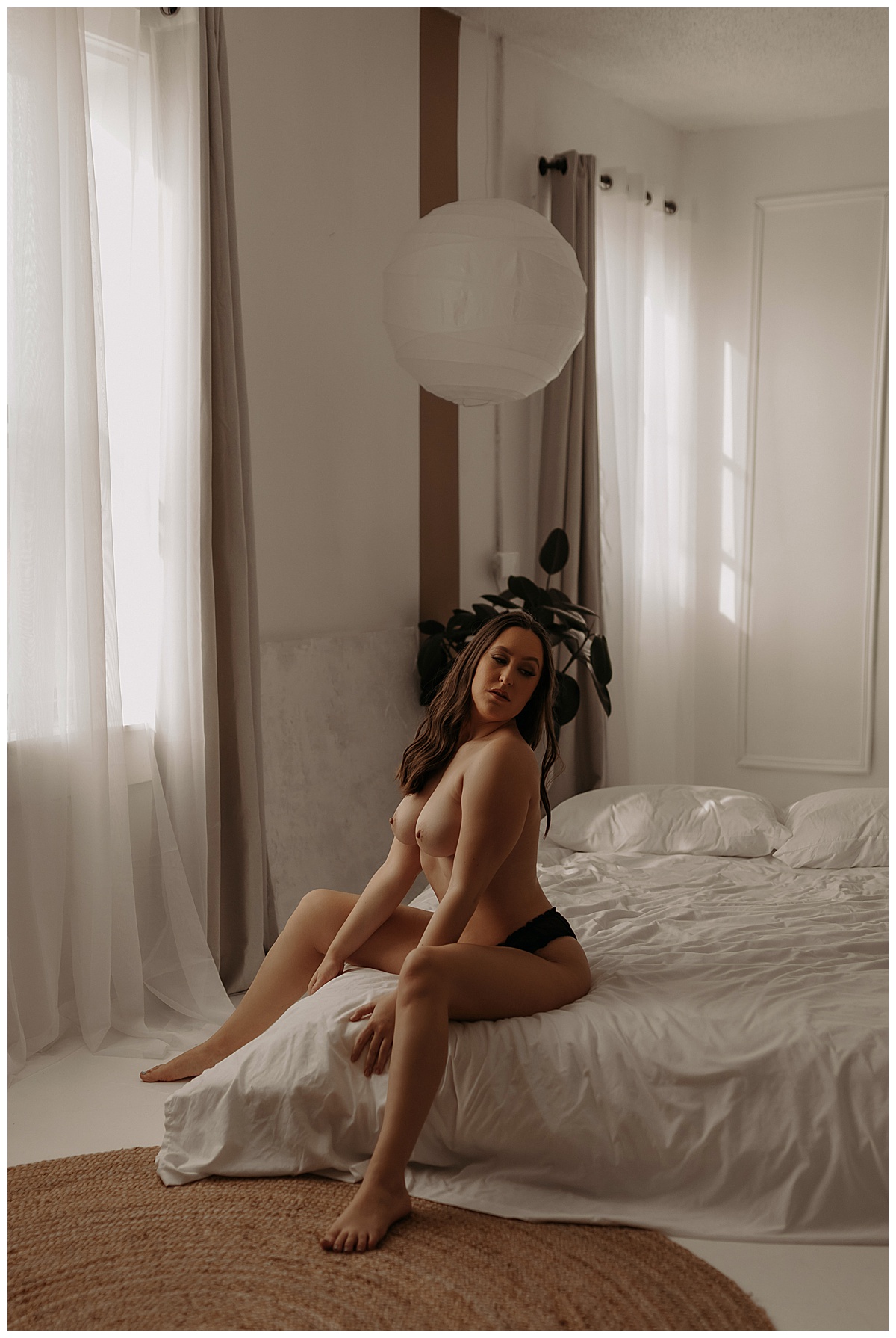Woman sits on the edge of a bed showing the benefits of doing More Than One Boudoir Session