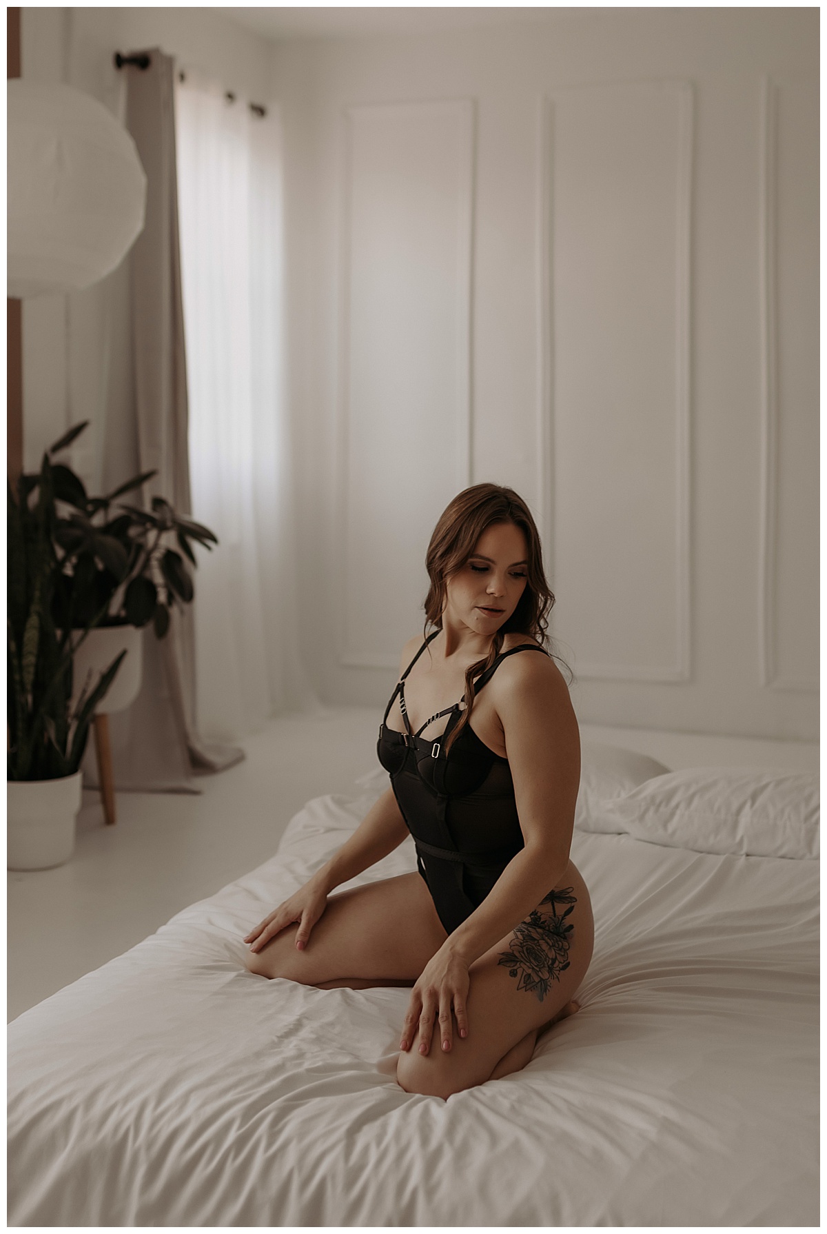 Woman kneels on the bed wearing black lingerie after Choosing The Right Boudoir Photographer