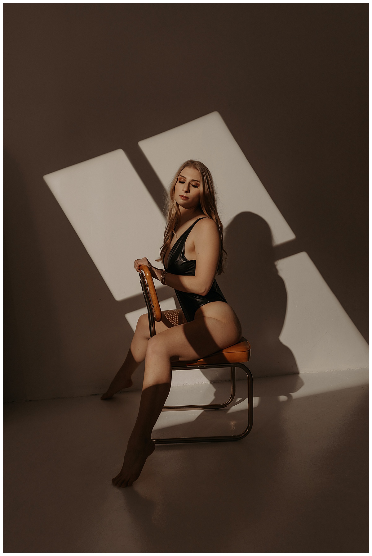 Adult sits on a chair wearing black lingerie for her Birthday Boudoir Session