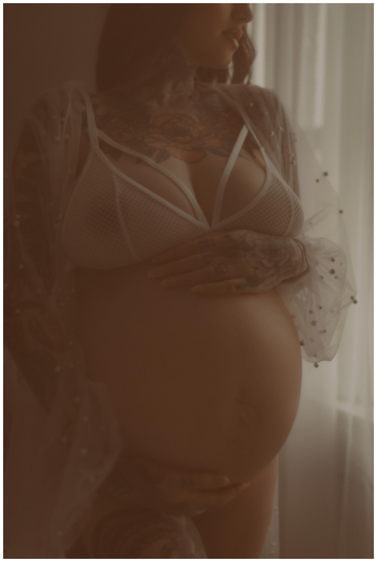 Adult looks over her shoulder holding her baby bump for Mary Castillo Photography