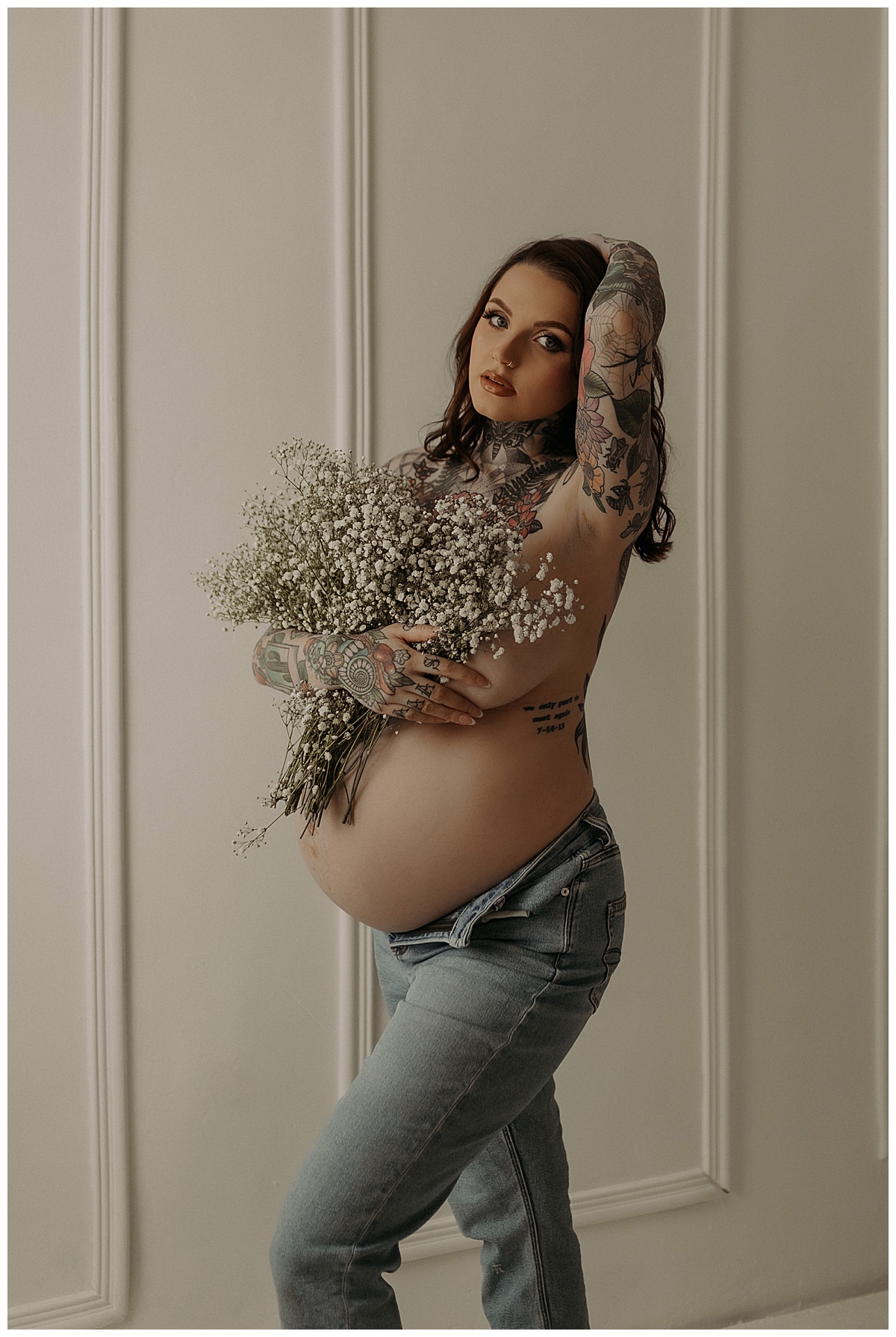 Woman holds floral bouquet during her Maternity Boudoir Session